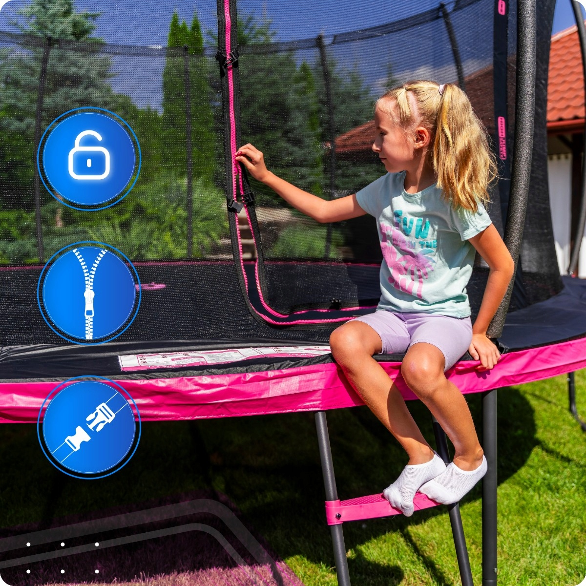 Dziewczynka siedzi na trampolinie, zapinając zamek.