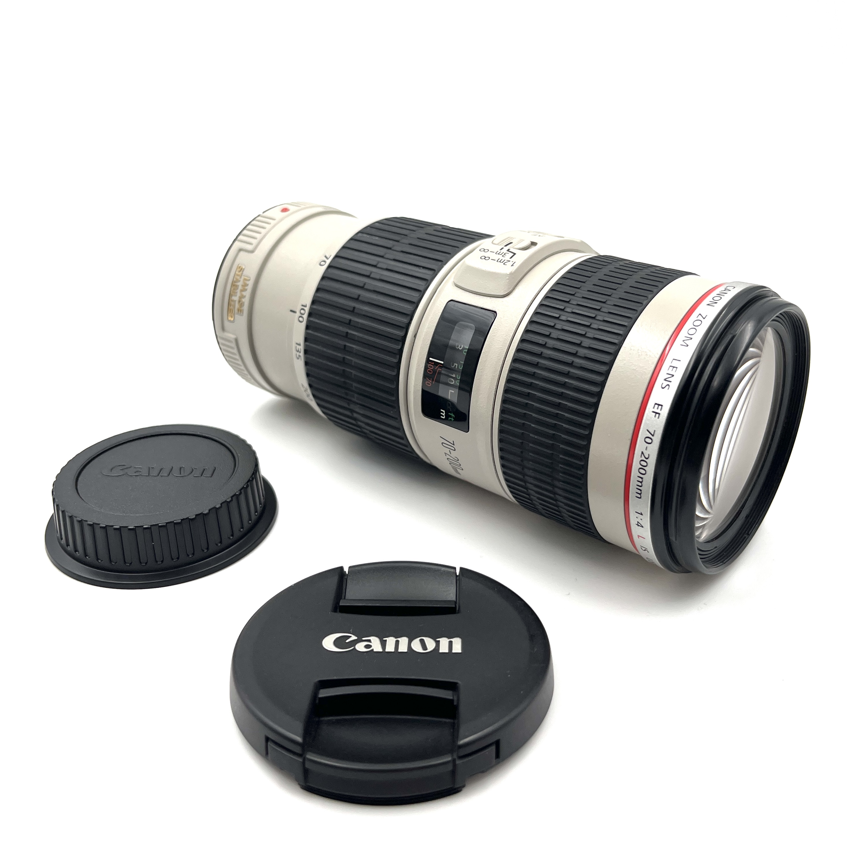Un obiettivo Canon EF 70-200mm con due tappi neri su sfondo bianco.