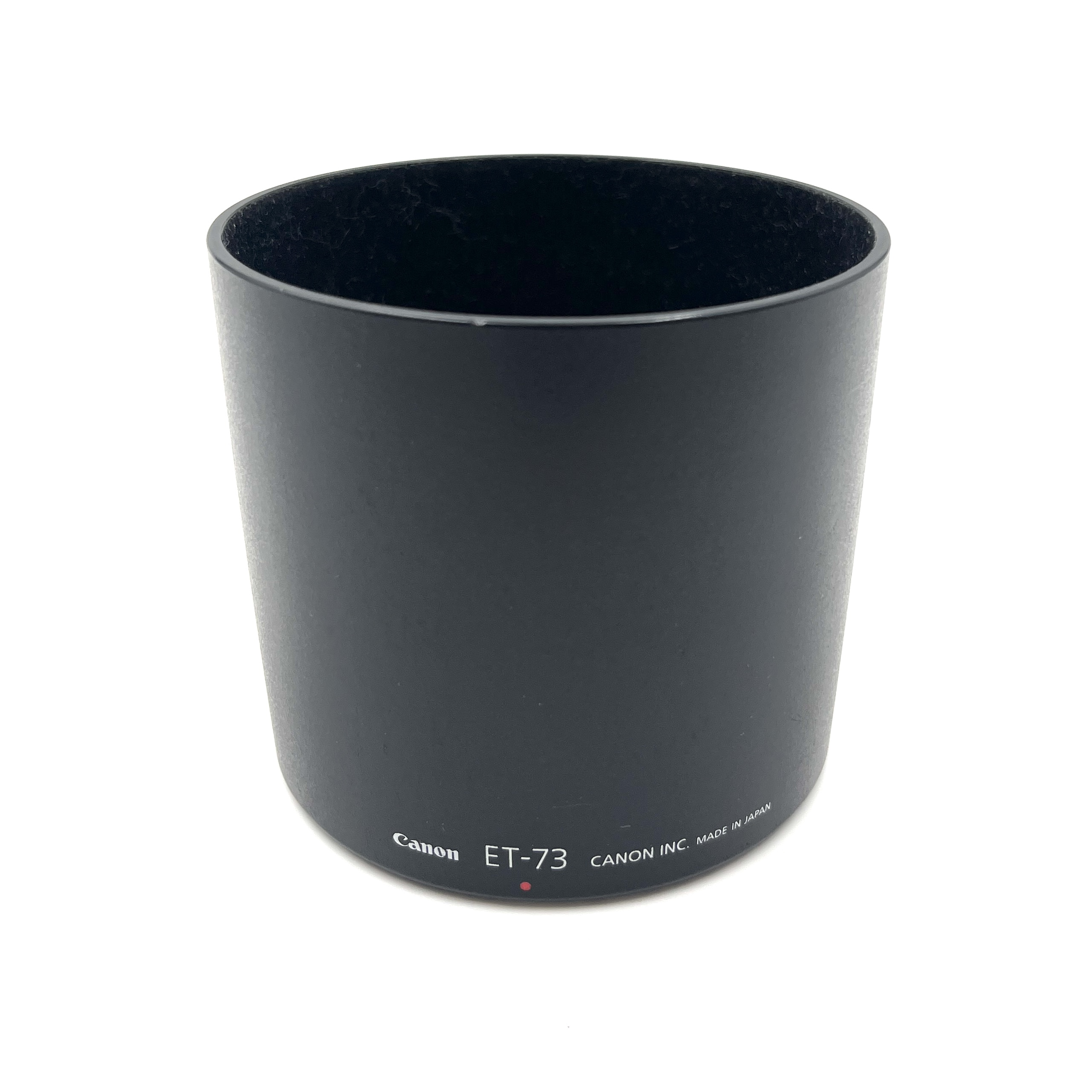 Czarna osłona obiektywu z napisem Canon ET-73, na białym tle.