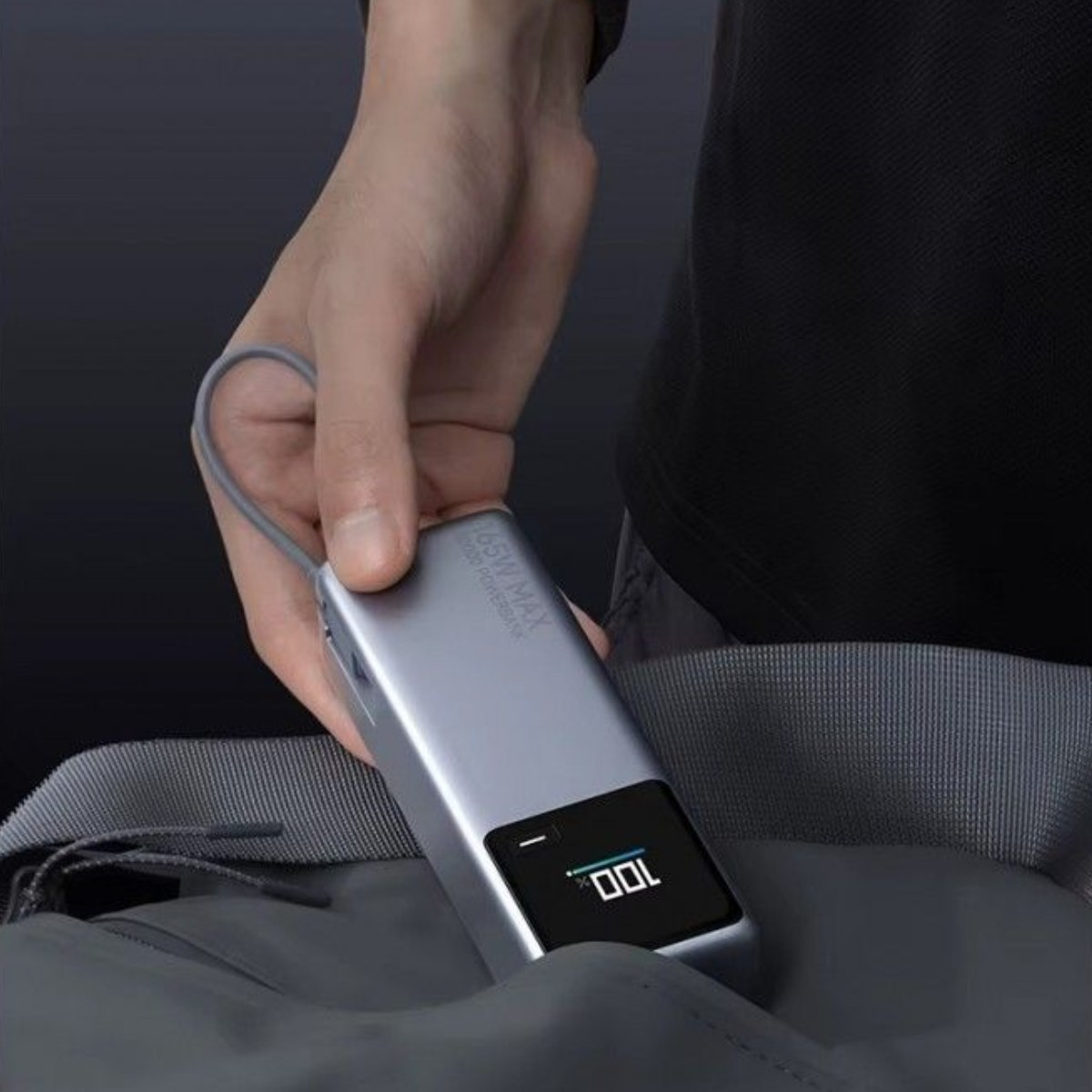 Dłoń trzyma srebrny powerbank, na ekranie którego wyświetla się 100%.