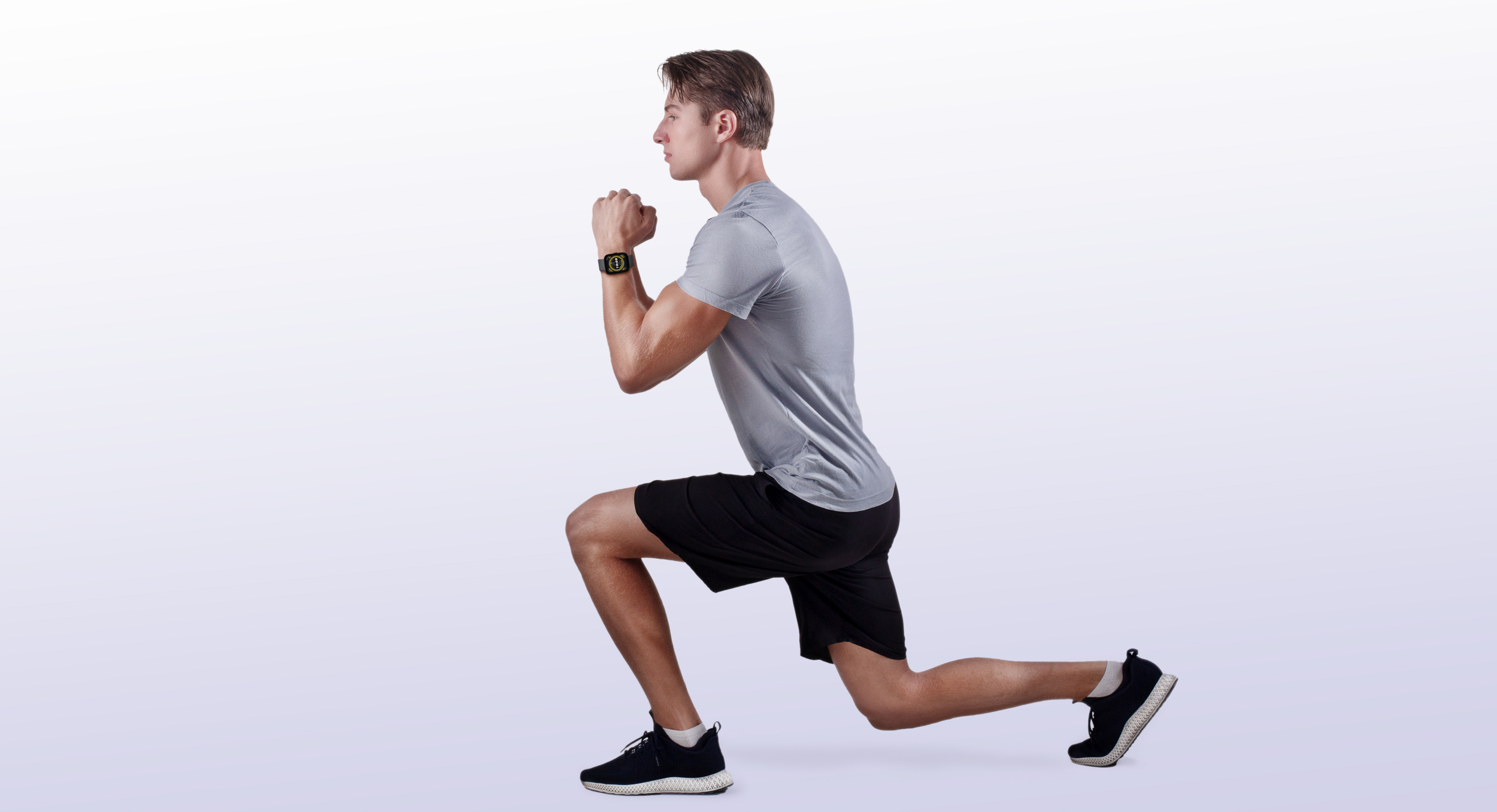 Mężczyzna w szarym t-shircie i czarnych spodenkach wykonuje wykrok.