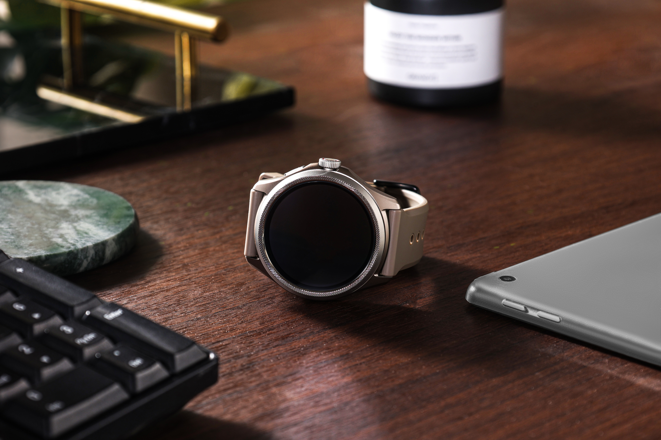 Srebrny smartwatch z czarnym ekranem na drewnianym biurku.