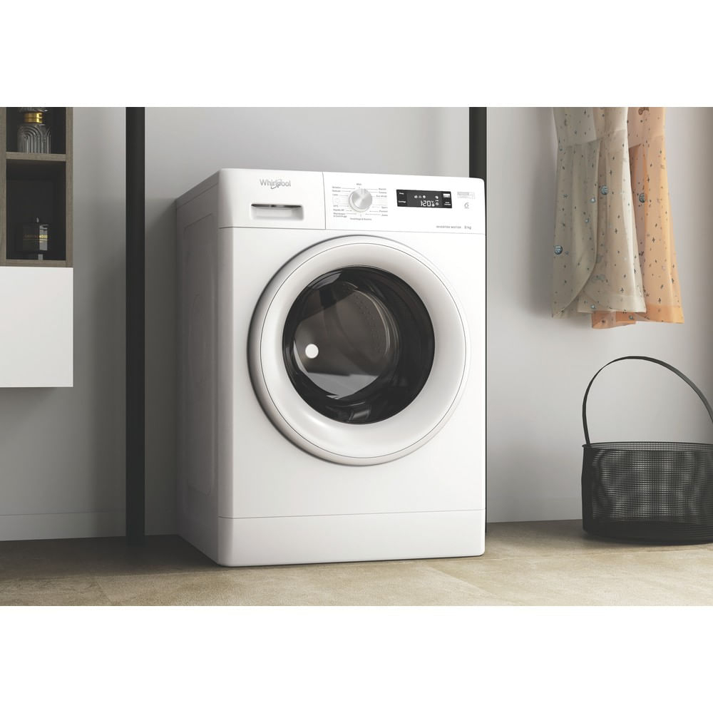 Una lavatrice Whirlpool bianca si trova in una stanza con vestiti e un cesto.