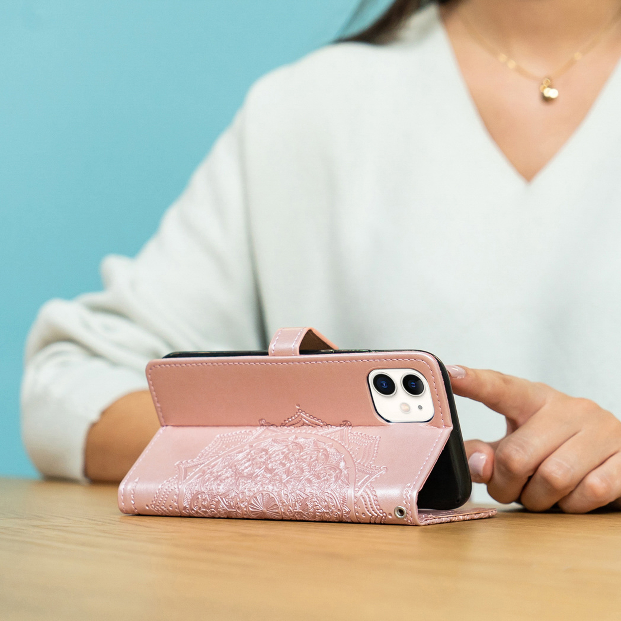 Een persoon die een roze telefoonhoes met mandala-reliëf vasthoudt.