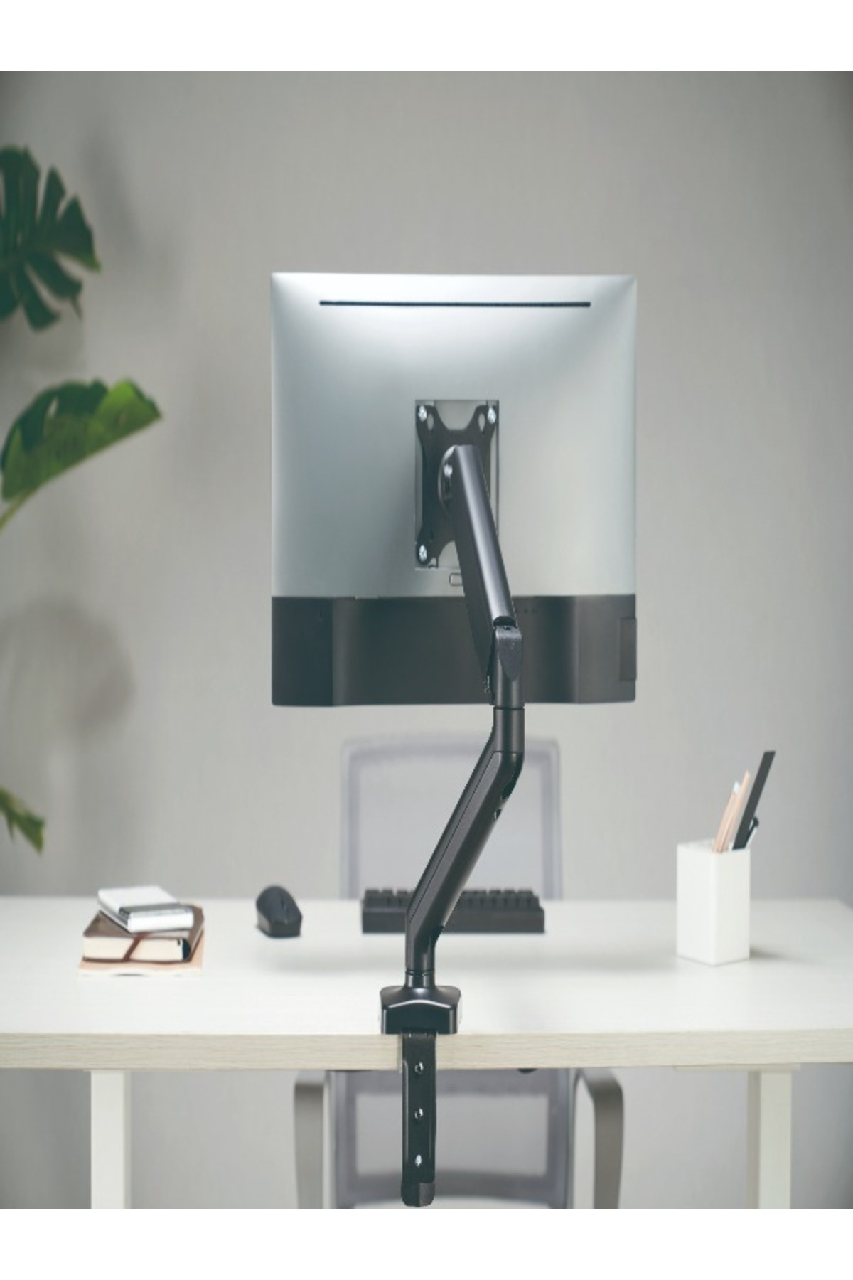 Monitör kolu, masanın üzerinde gümüş rengi bir monitörü tutuyor.