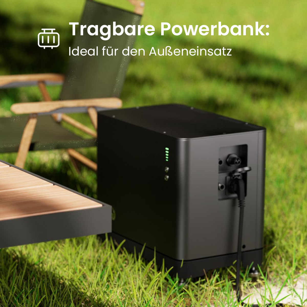 Schwarze Powerbank im Gras neben einem Tisch und Stuhl.