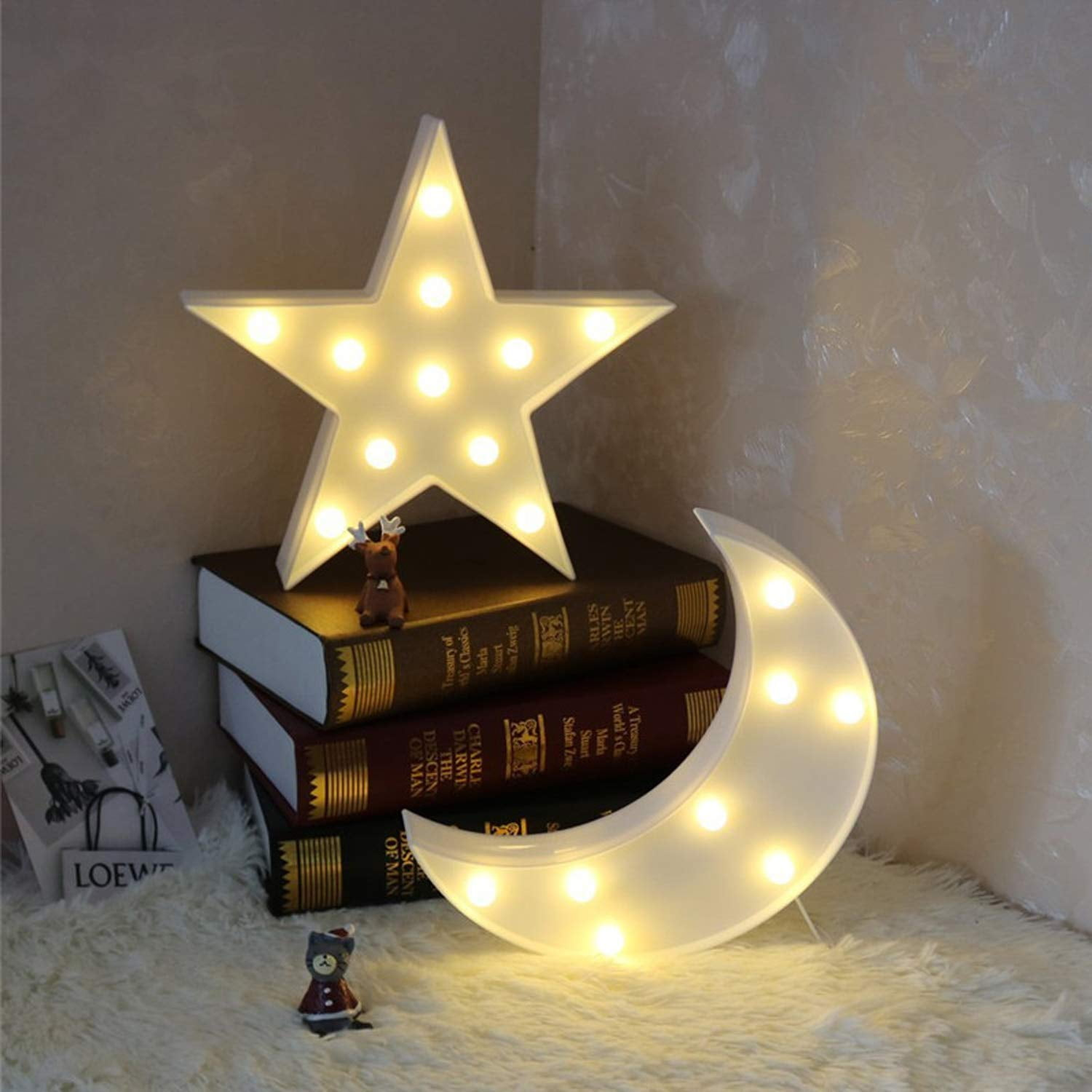 Ein leuchtender Stern und Mond stehen auf Büchern. Kleine Figuren sind davor.
