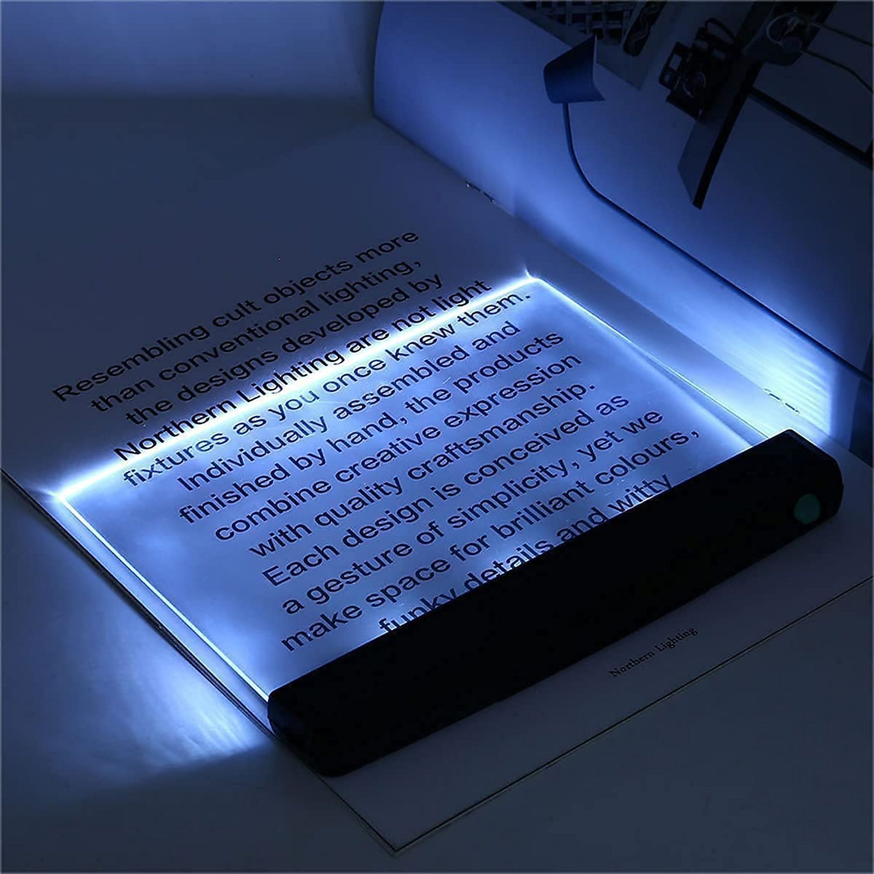 Ein Buch mit beleuchteten Seiten und einem schwarzen Lesegerät. Texte sind sichtbar.