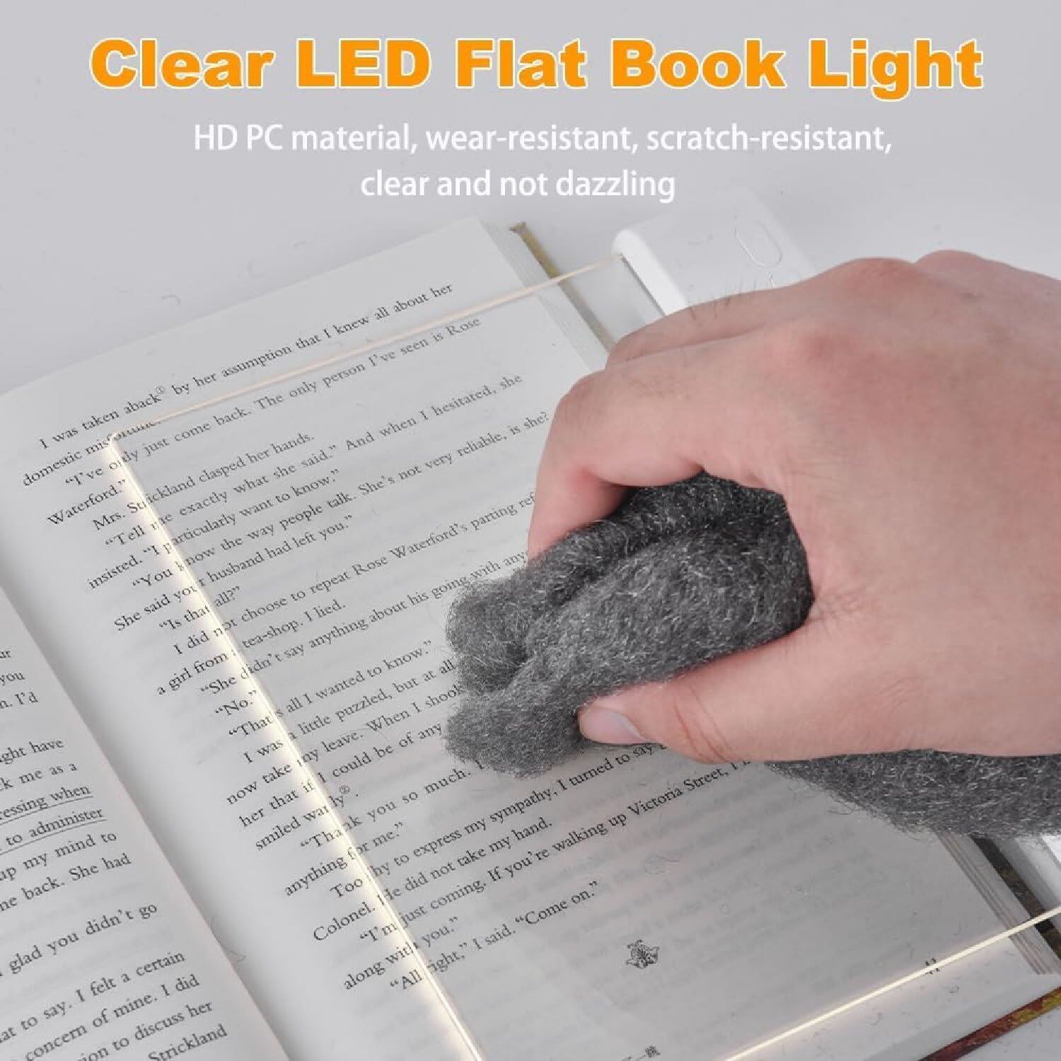 Hand wischt über offenes Buch, auf dem ein LED-Buchlicht montiert ist.
