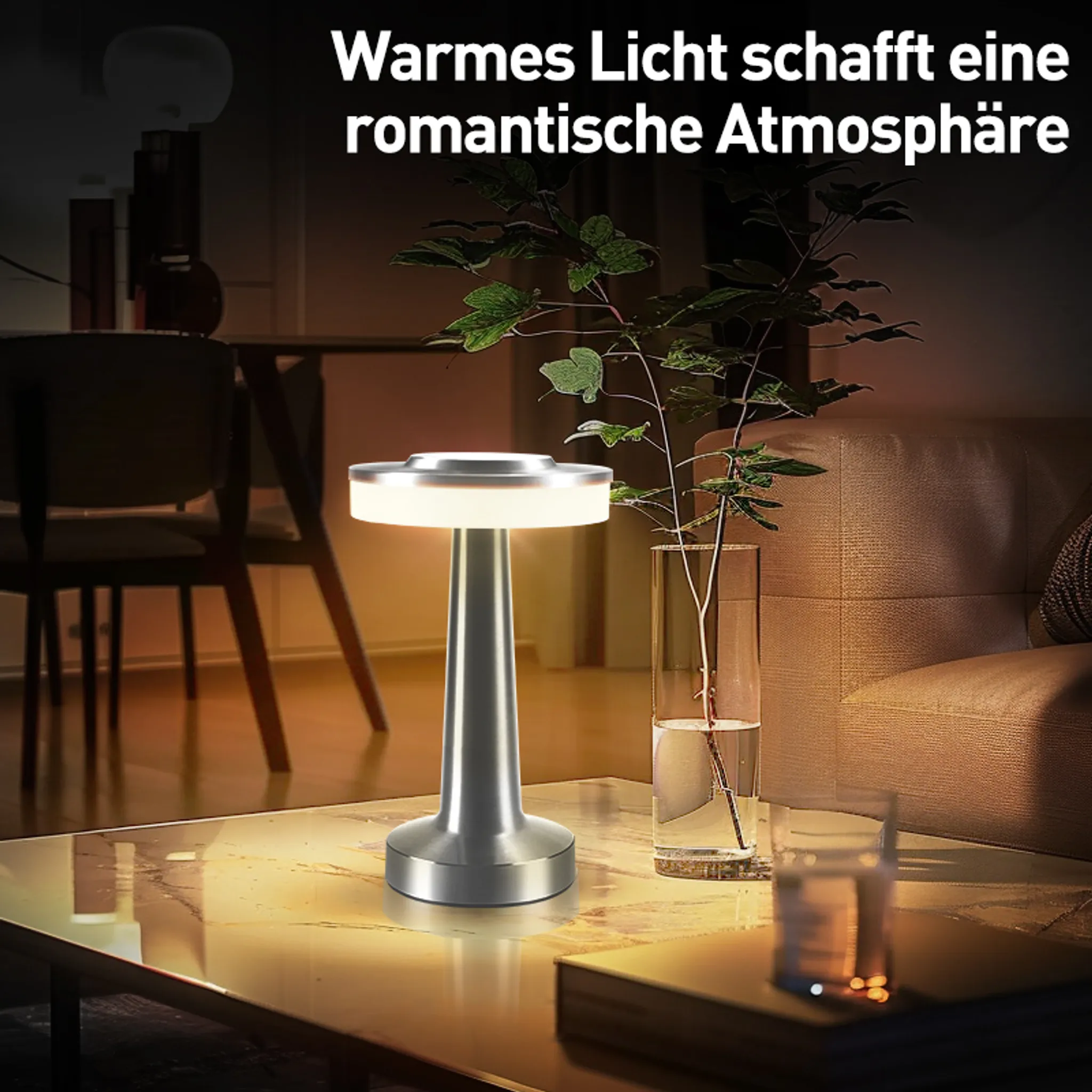 Eine silberne Lampe steht auf einem Tisch mit Pflanzen und einem Glas.