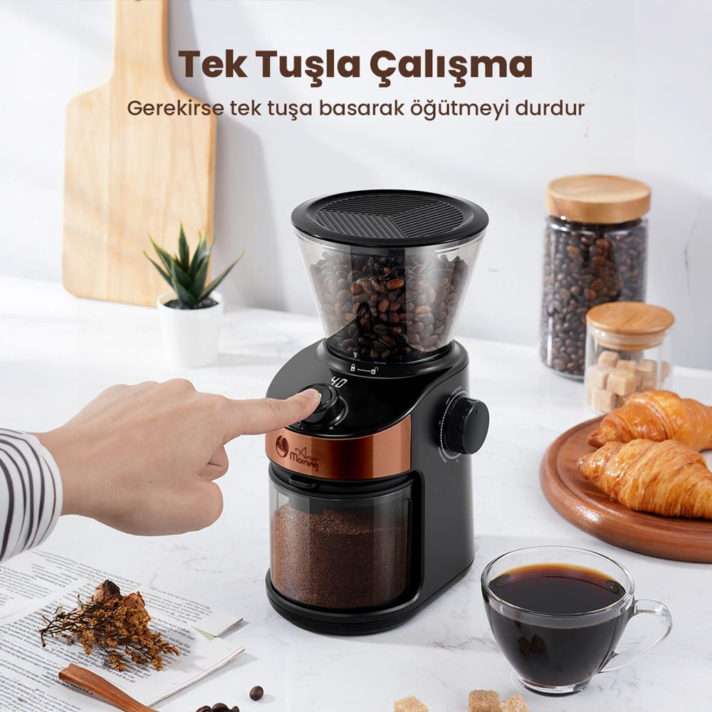 Bir el, çekirdek dolu kahve öğütücünün düğmesine basar. Yakında öğütülmüş kahve, kruvasan ve kahve bulunur.