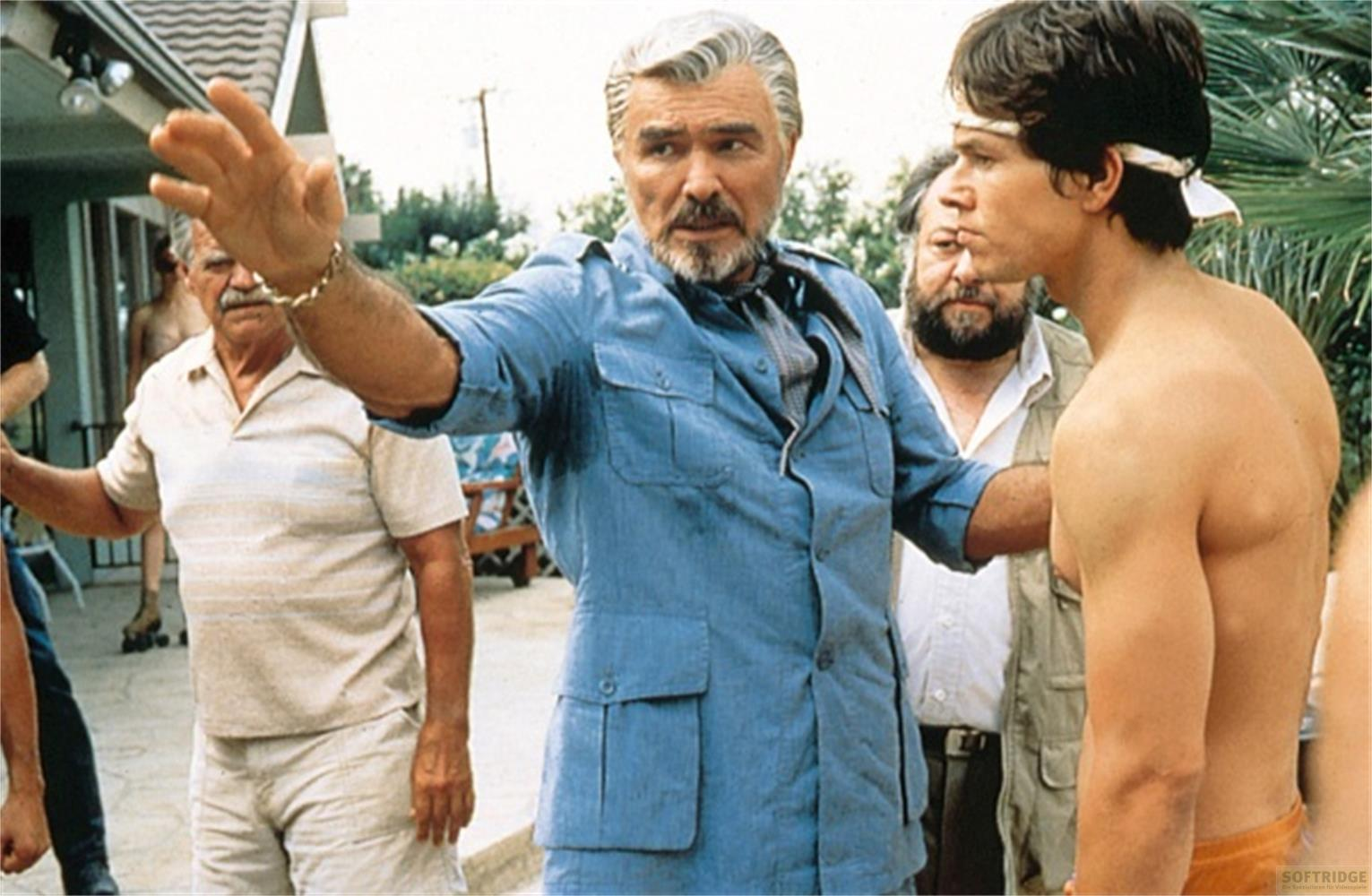 Tre uomini fuori. Uno in camicia blu fa un gesto con la mano.