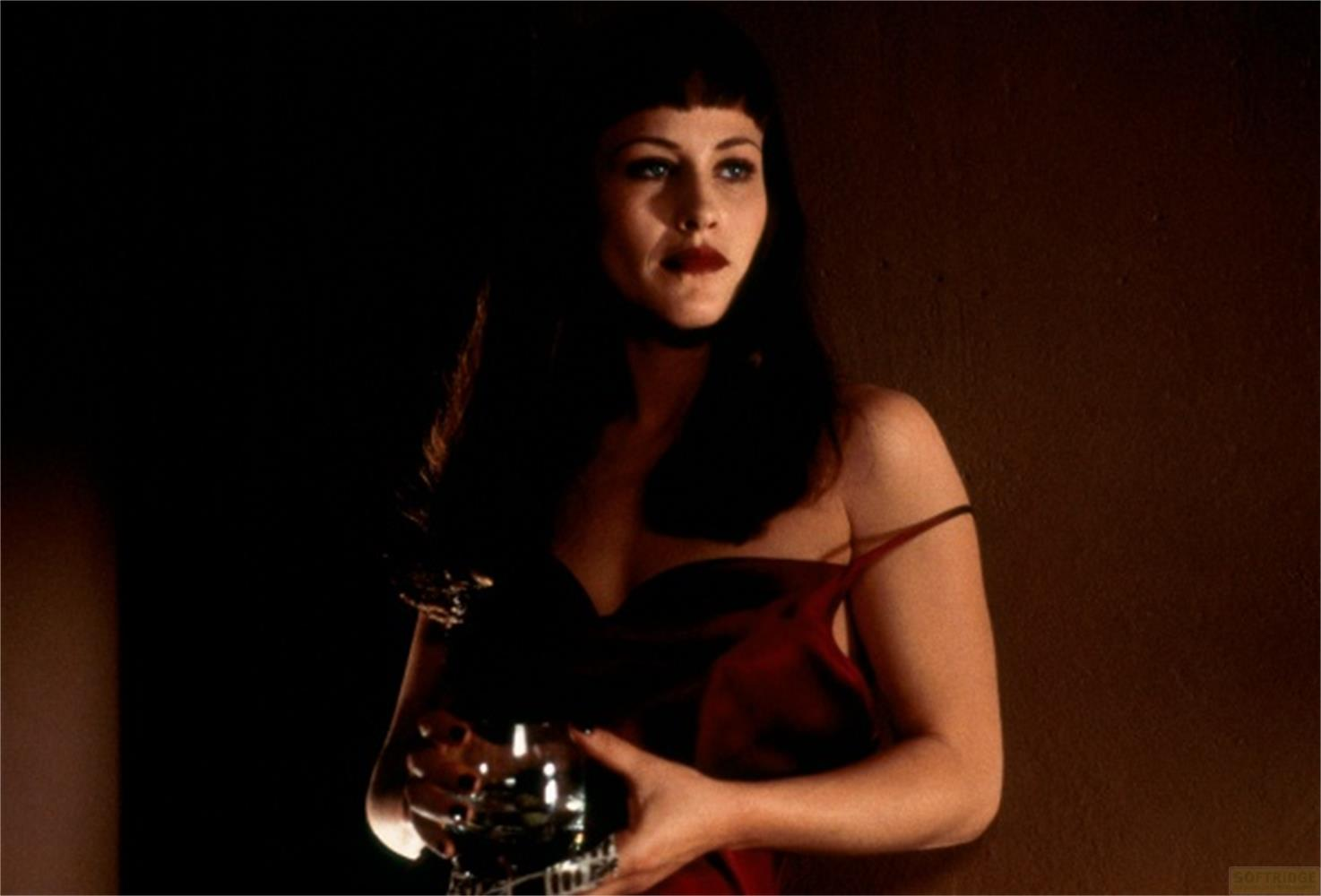 Una donna in abito rosso tiene un globo di vetro in un ambiente buio.