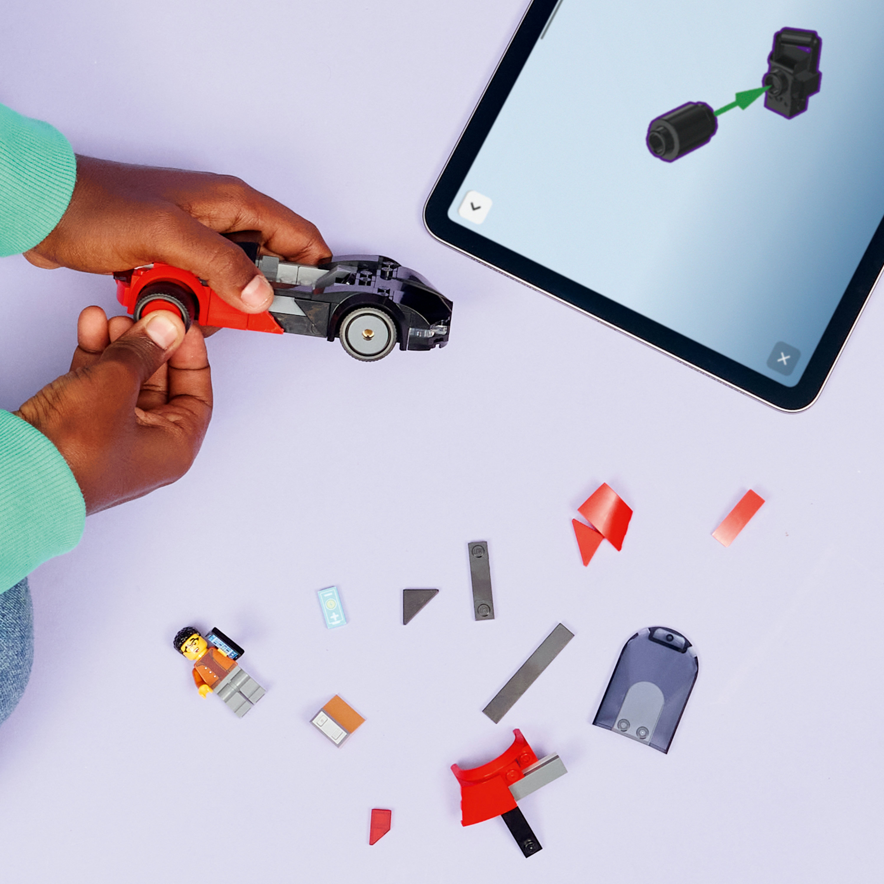 Dziecko buduje czerwony samochód z klocków, tablet pokazuje instrukcje.