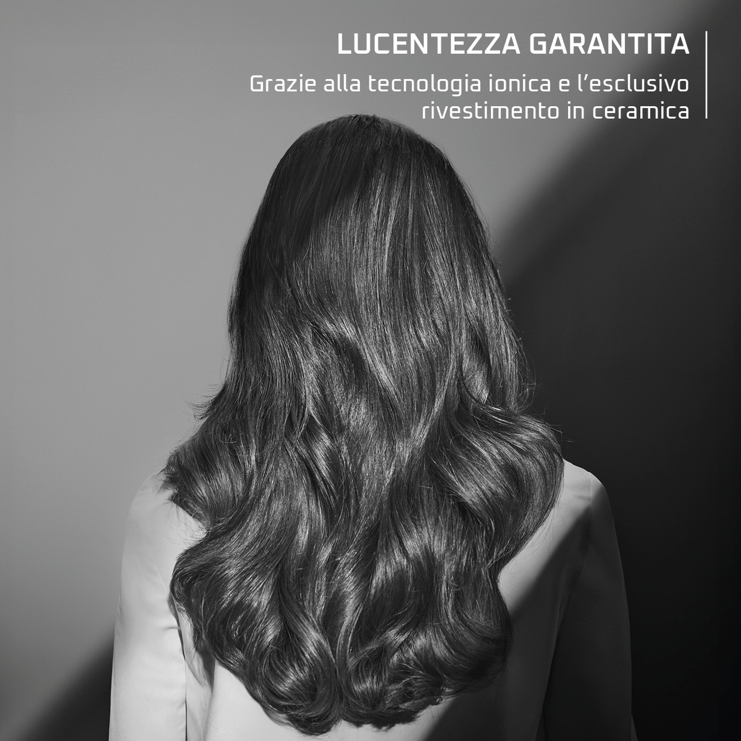Vista posteriore di una donna con lunghi capelli scuri e mossi e un top chiaro.