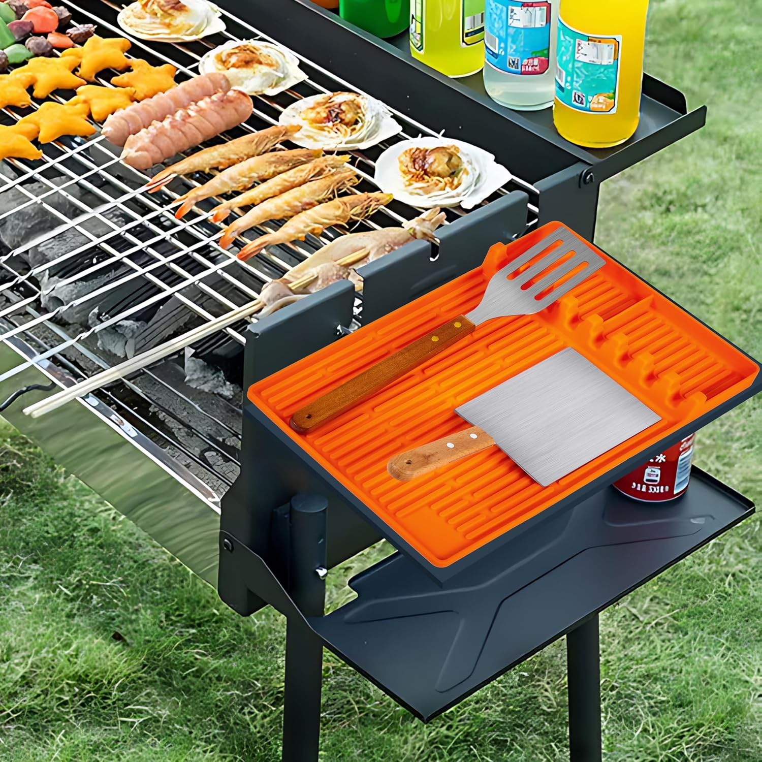 Grill mit Würstchen, Garnelen, Jakobsmuscheln und Sternen-Nuggets, daneben Kochutensilien.