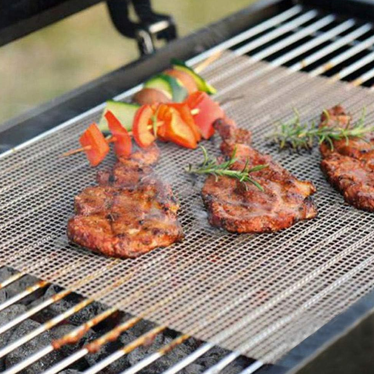 Steak und Gemüsespieße grillen auf einer Netzmatte über heißen Kohlen.