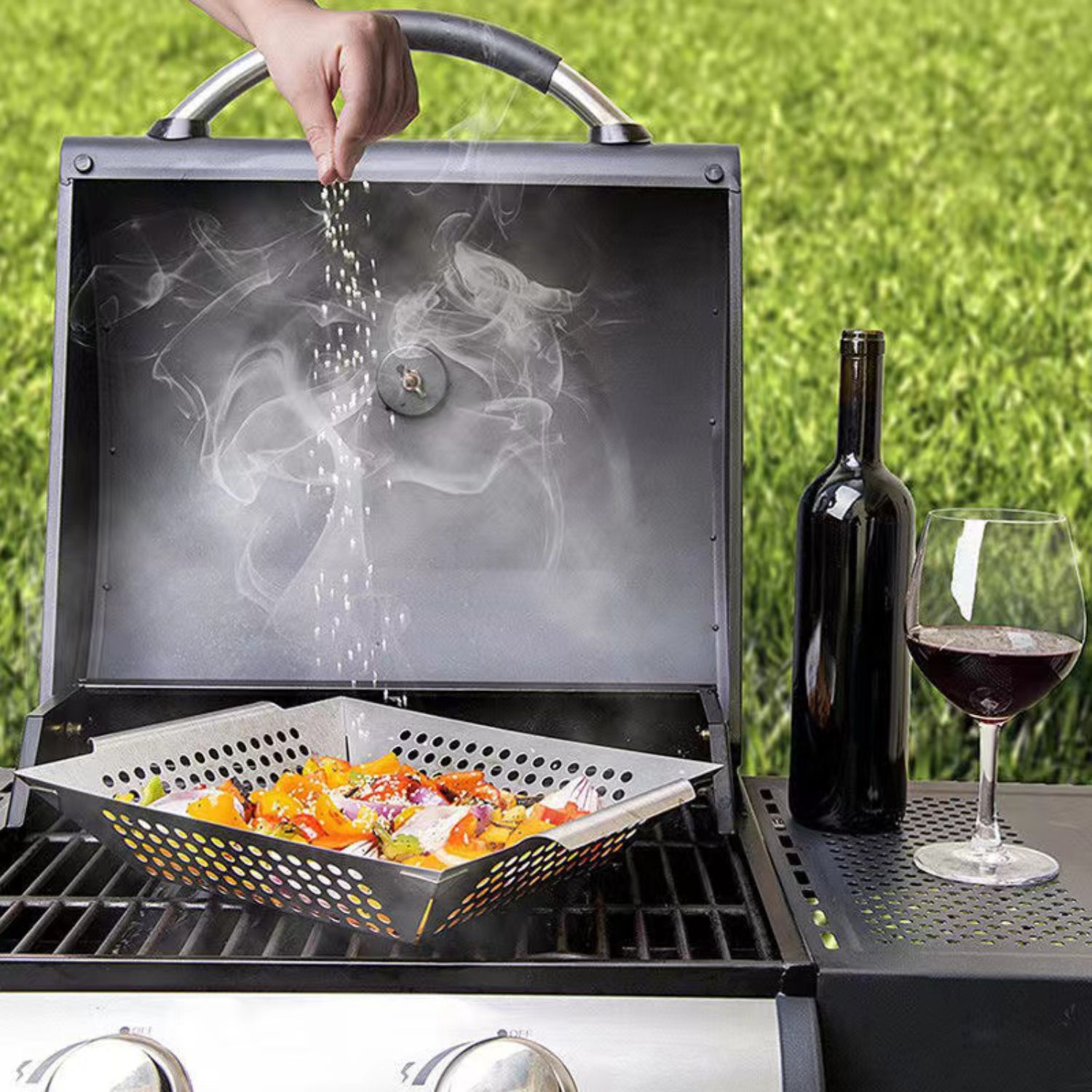 Eine Hand würzt Gemüse auf einem Grill mit Rauch und einem Glas Rotwein.