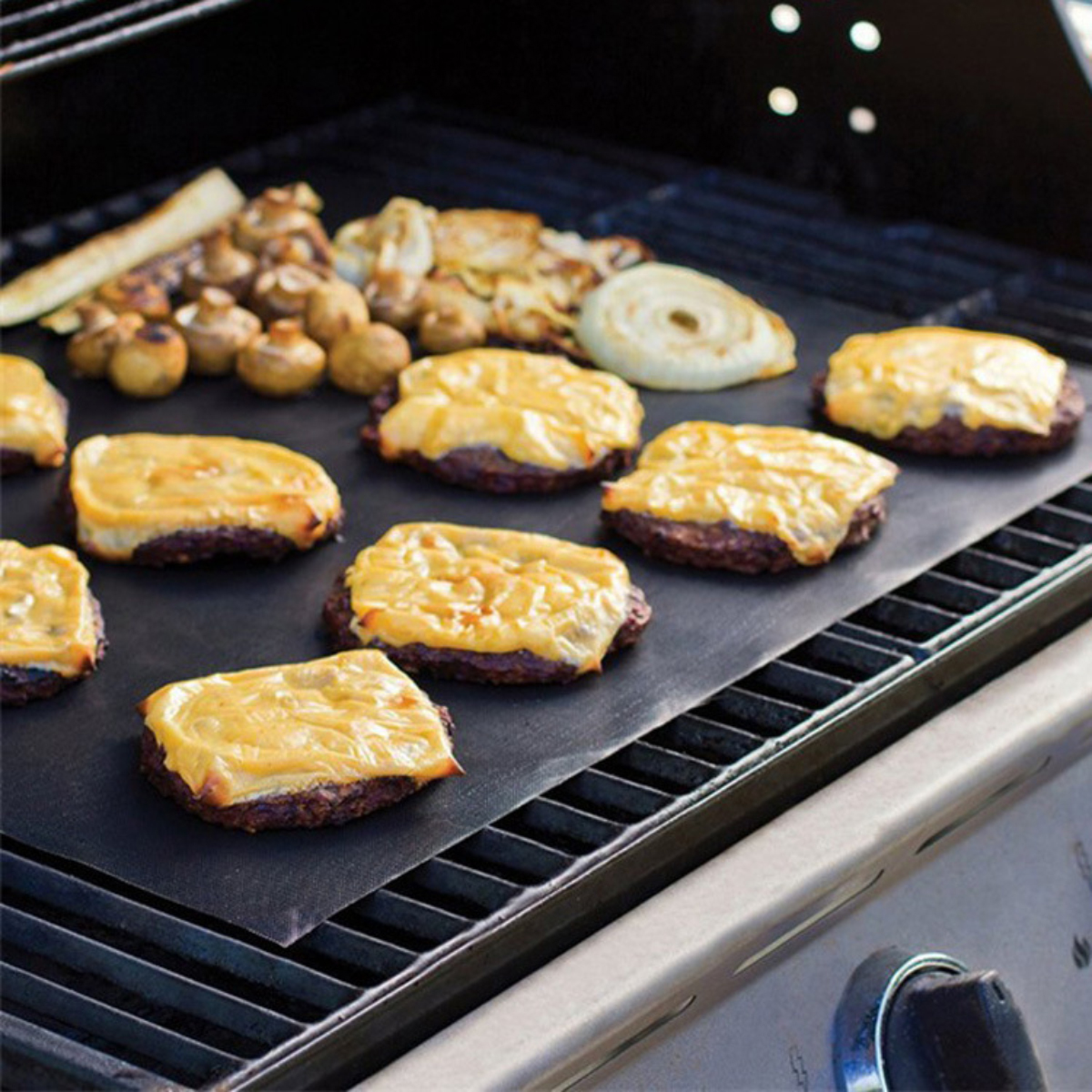 Burger mit geschmolzenem Käse und Gemüse auf einem Grillrost.