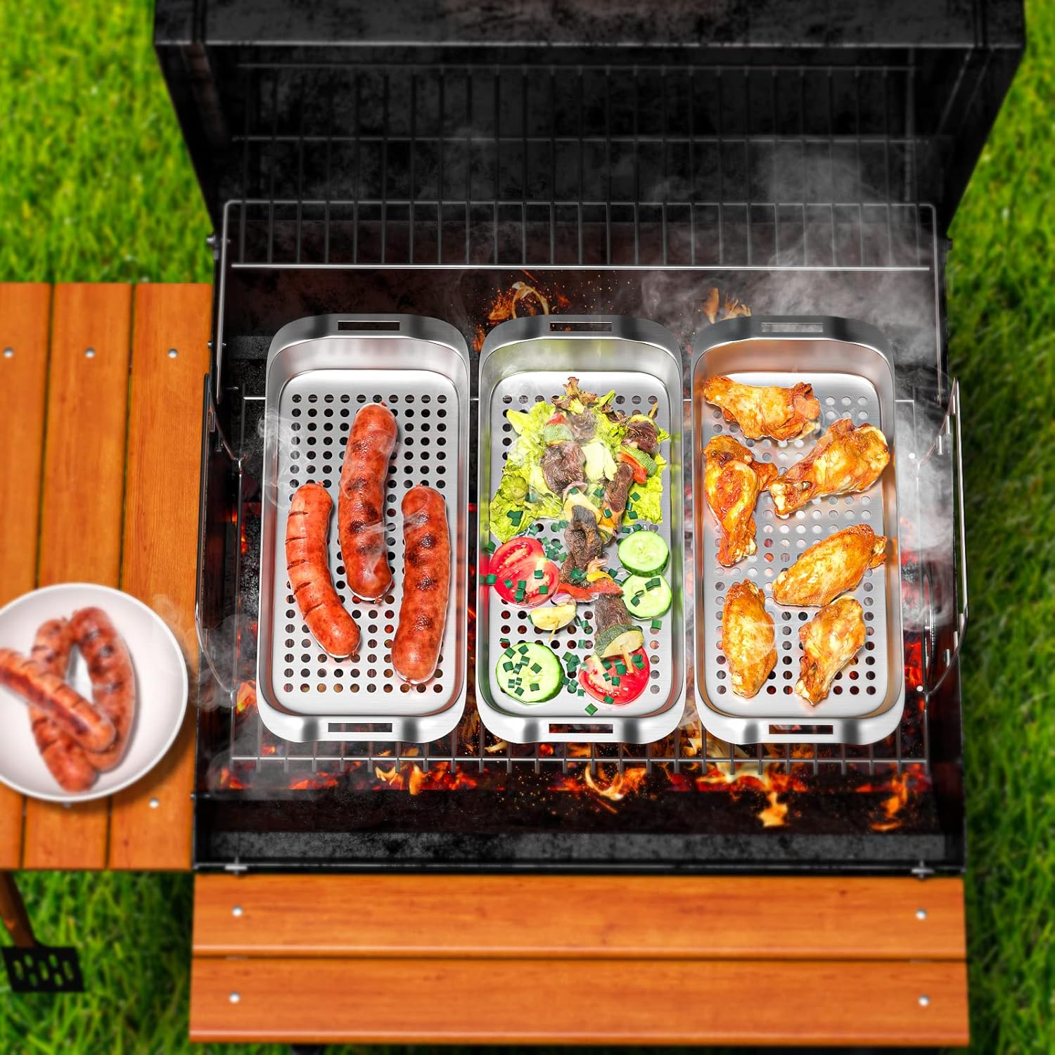 Grill mit Würstchen, Salat und Hähnchenflügeln auf dem Rost, Rauch steigt auf.
