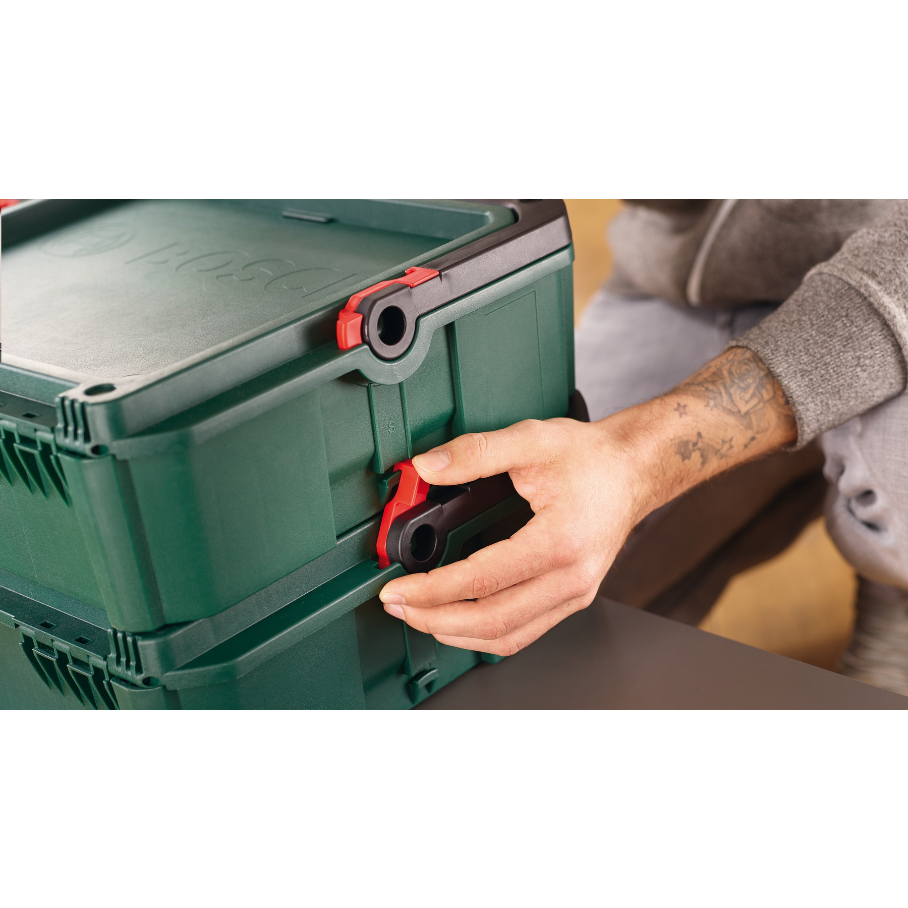 Mano opera fermo rosso e nero su cassetta degli attrezzi Bosch verde.