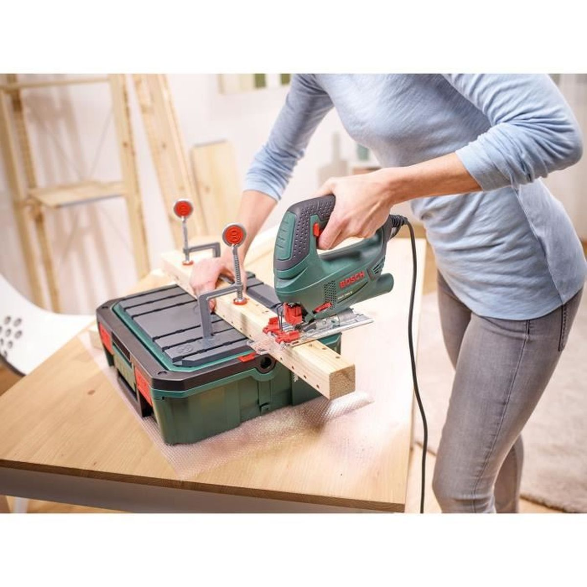 Persona taglia legno con seghetto alternativo su banco da lavoro. Sega verde, assi.