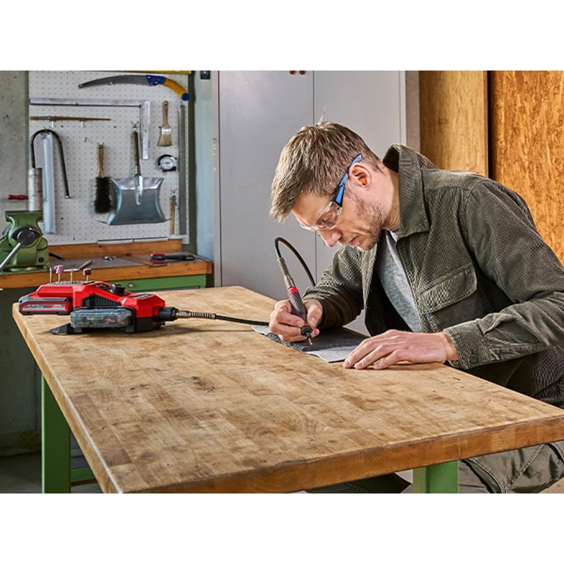 Homme avec lunettes de sécurité utilise un outil de gravure sur établi.