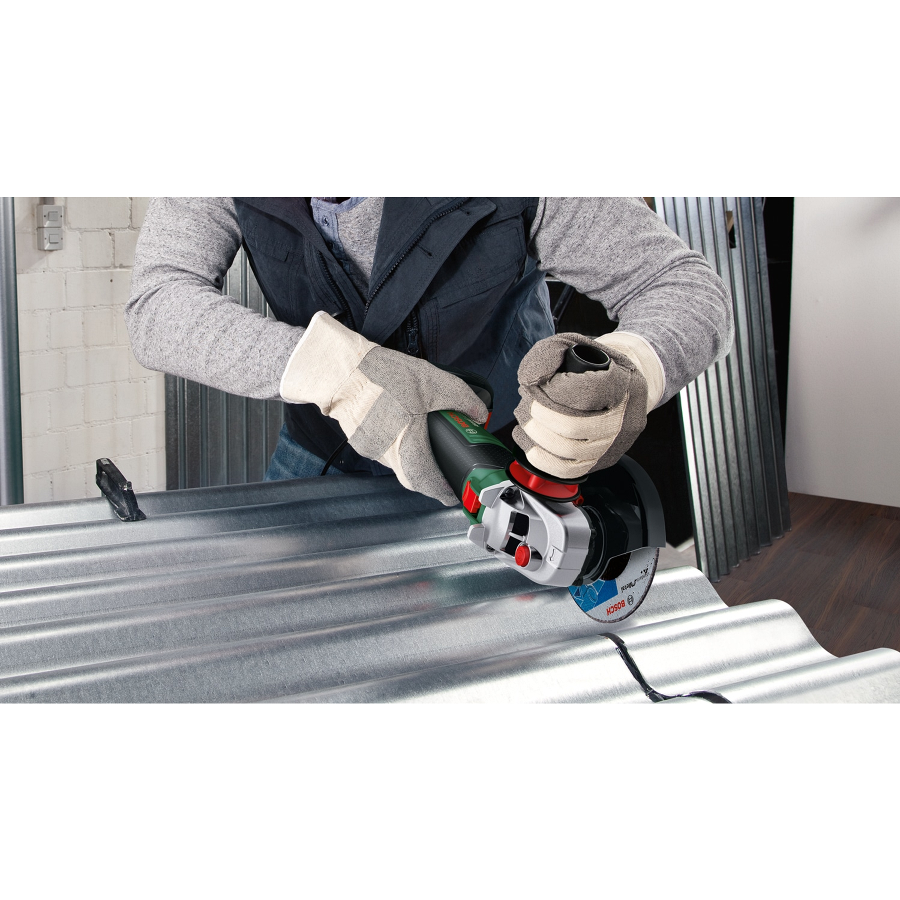 Ein Handwerker mit Handschuhen schneidet mit einem Winkelschleifer Metall.