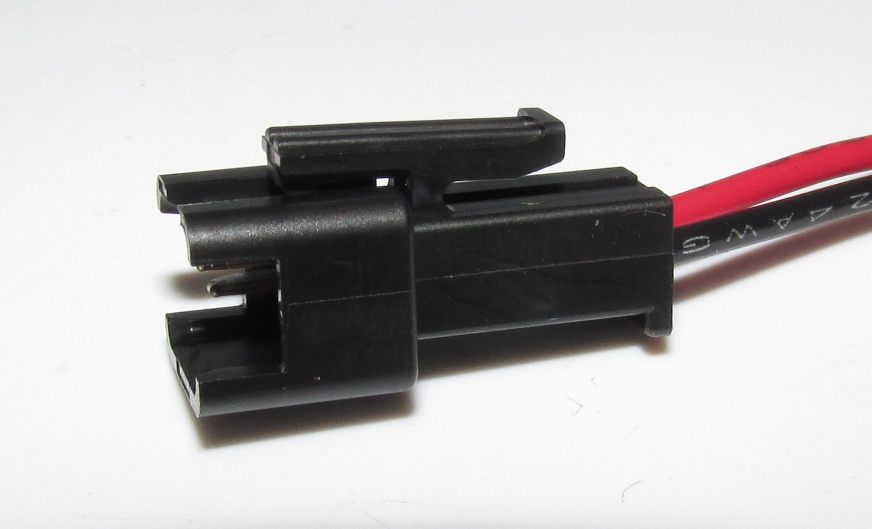 Ein schwarzer elektrischer Steckverbinder mit roten und schwarzen Kabeln.