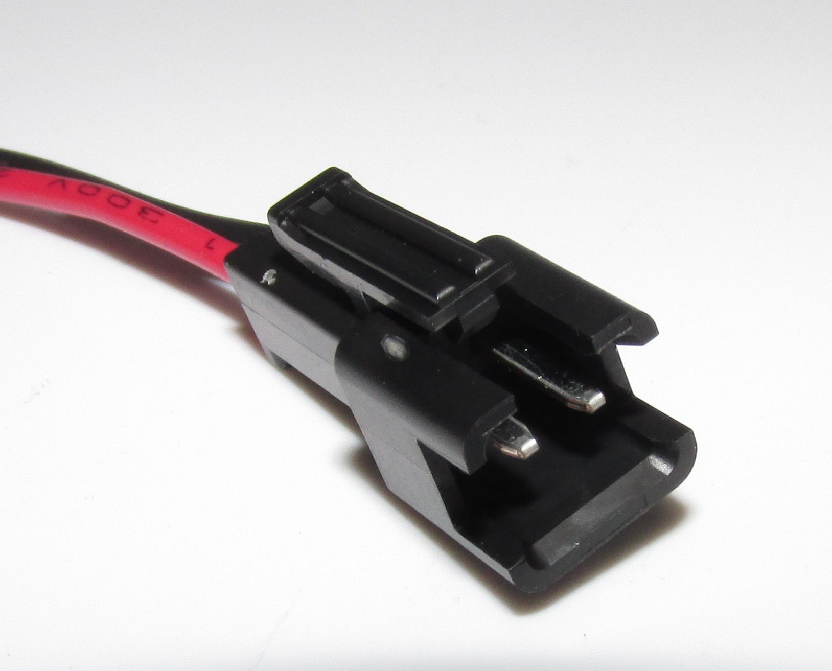 Ein schwarzer Stecker mit einem roten Kabel. Nahaufnahme.