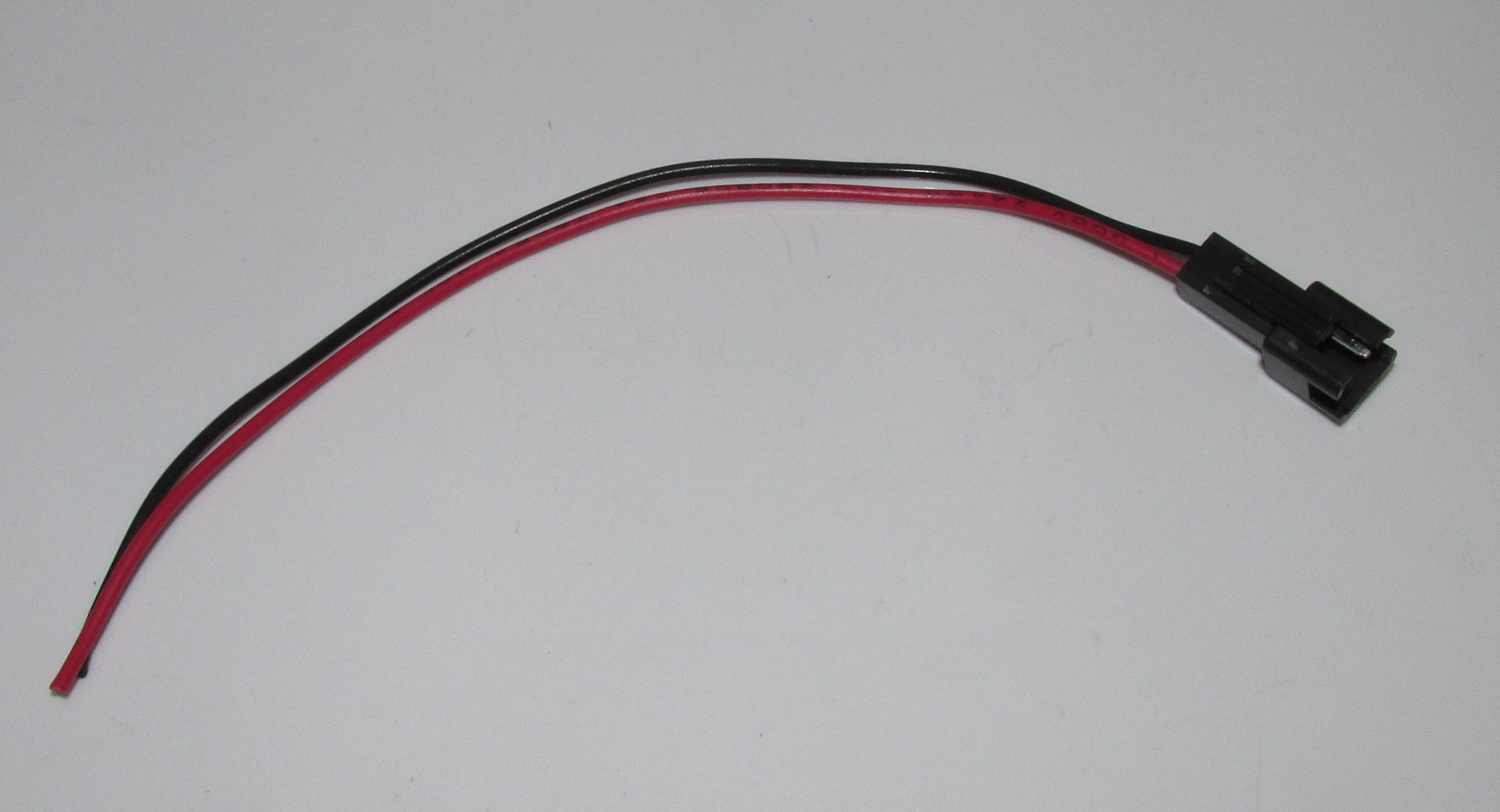Ein schwarzer und ein roter Draht mit schwarzem Stecker auf weißem Hintergrund.