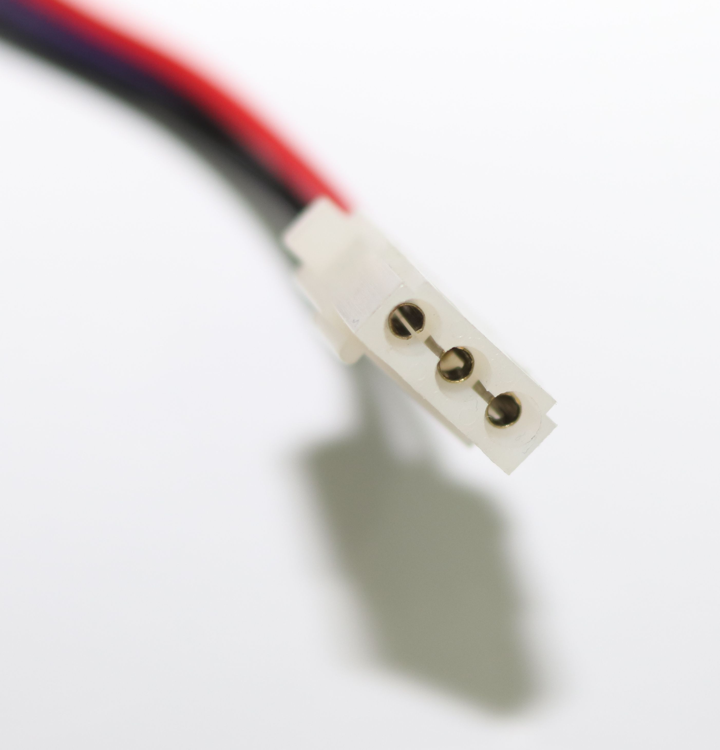 Ein weißer Stecker mit drei Kontakten und einem Kabel mit roten, blauen und schwarzen Drähten.