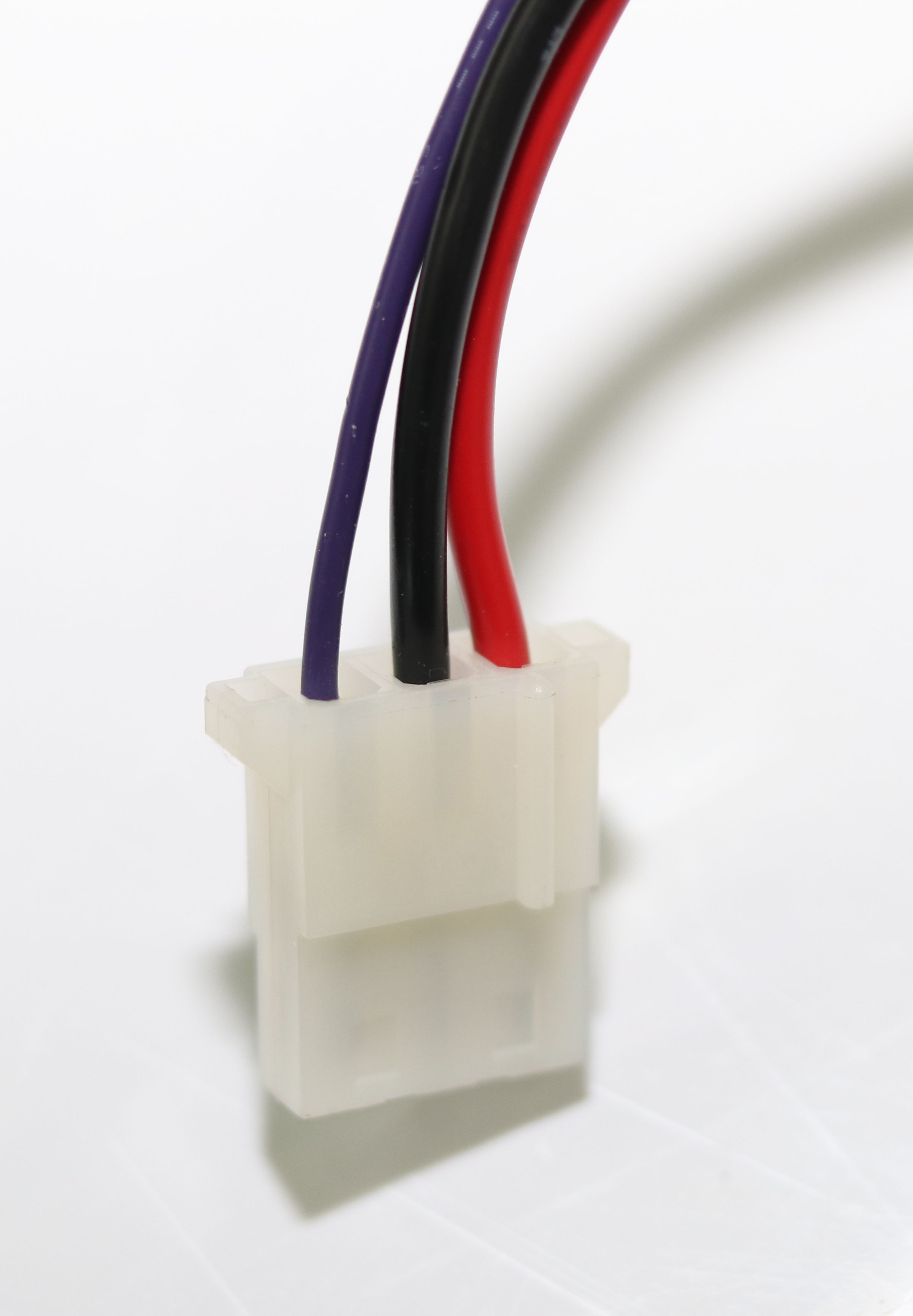 Ein weißer Stecker mit drei Kabeln: lila, schwarz und rot.