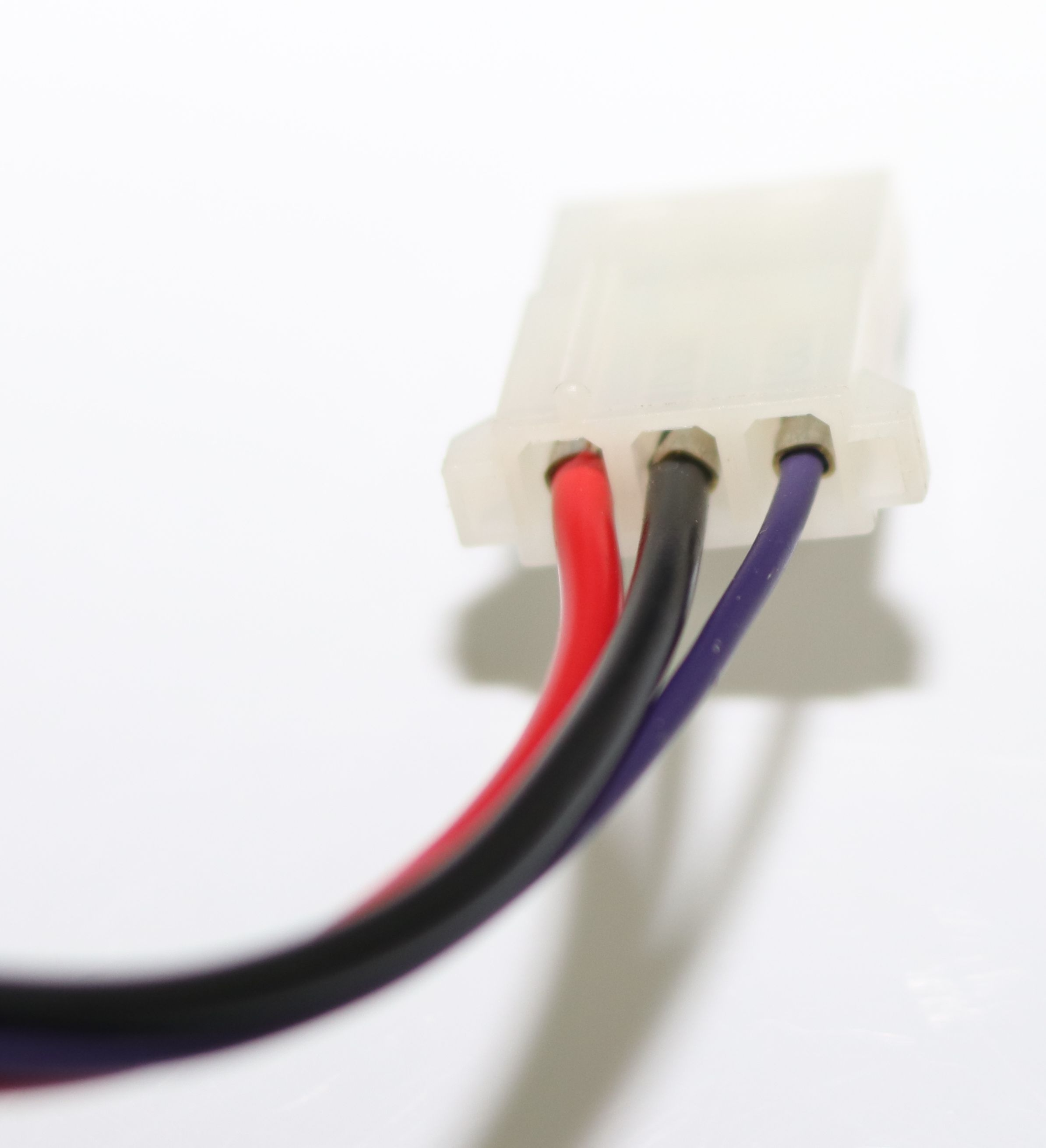 Ein weißer Stecker mit drei Kabeln: rot, schwarz und lila.