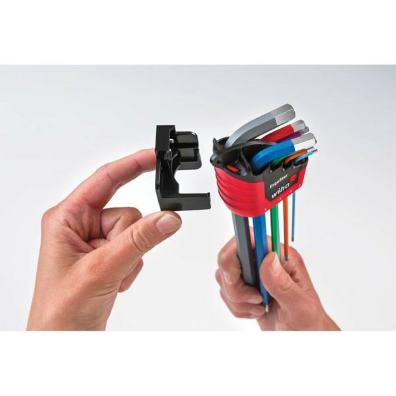 Eine Hand hält einen schwarzen Halter, während die andere Hand einen Satz bunter Inbusschlüssel hält.