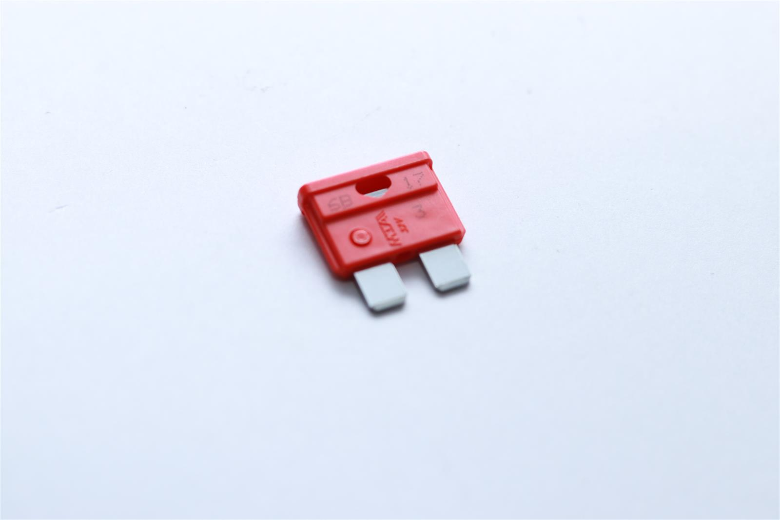 Ein roter Sicherungsstecker mit silbernen Pins auf weißem Hintergrund.
