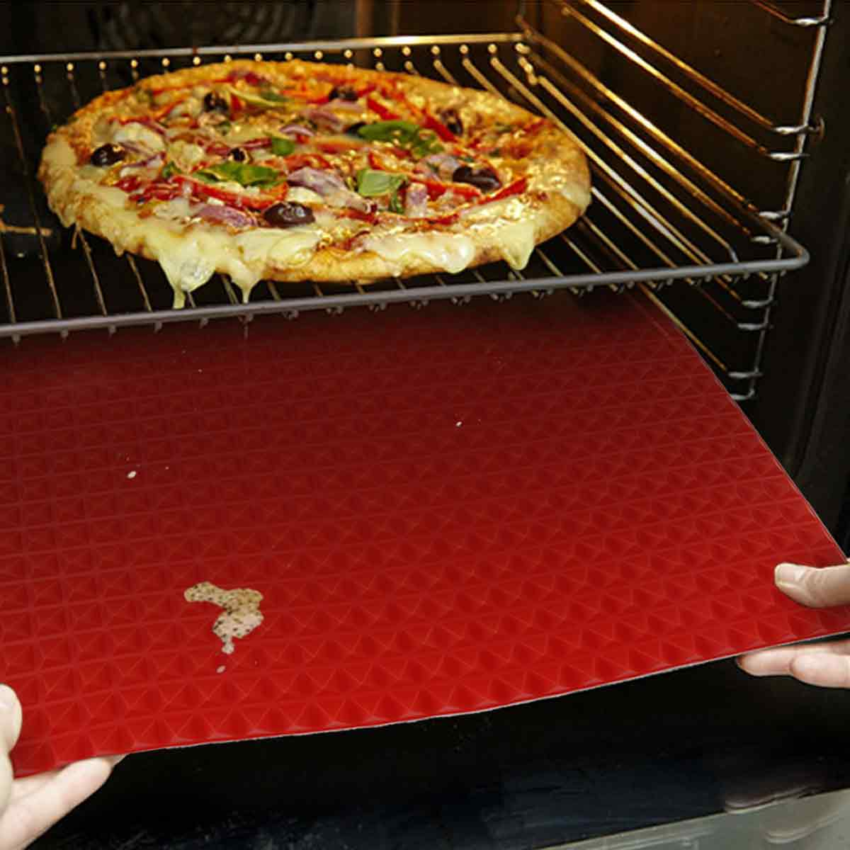 Ein gebackener Pizza wird aus dem Ofen auf eine rote Matte gehoben.