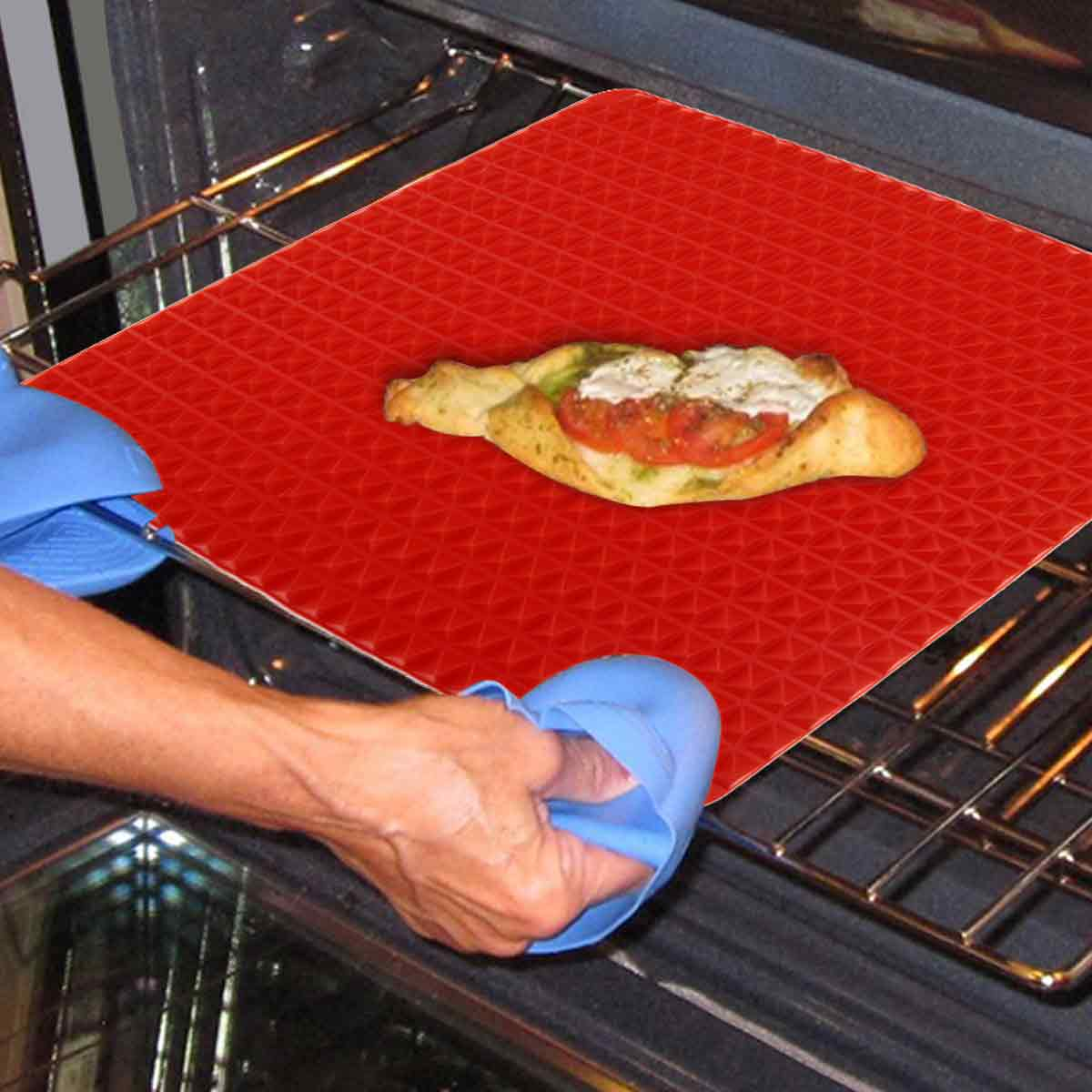 Person nimmt mit blauen Ofenhandschuhen ein Blech mit einer Pizza aus dem Ofen.