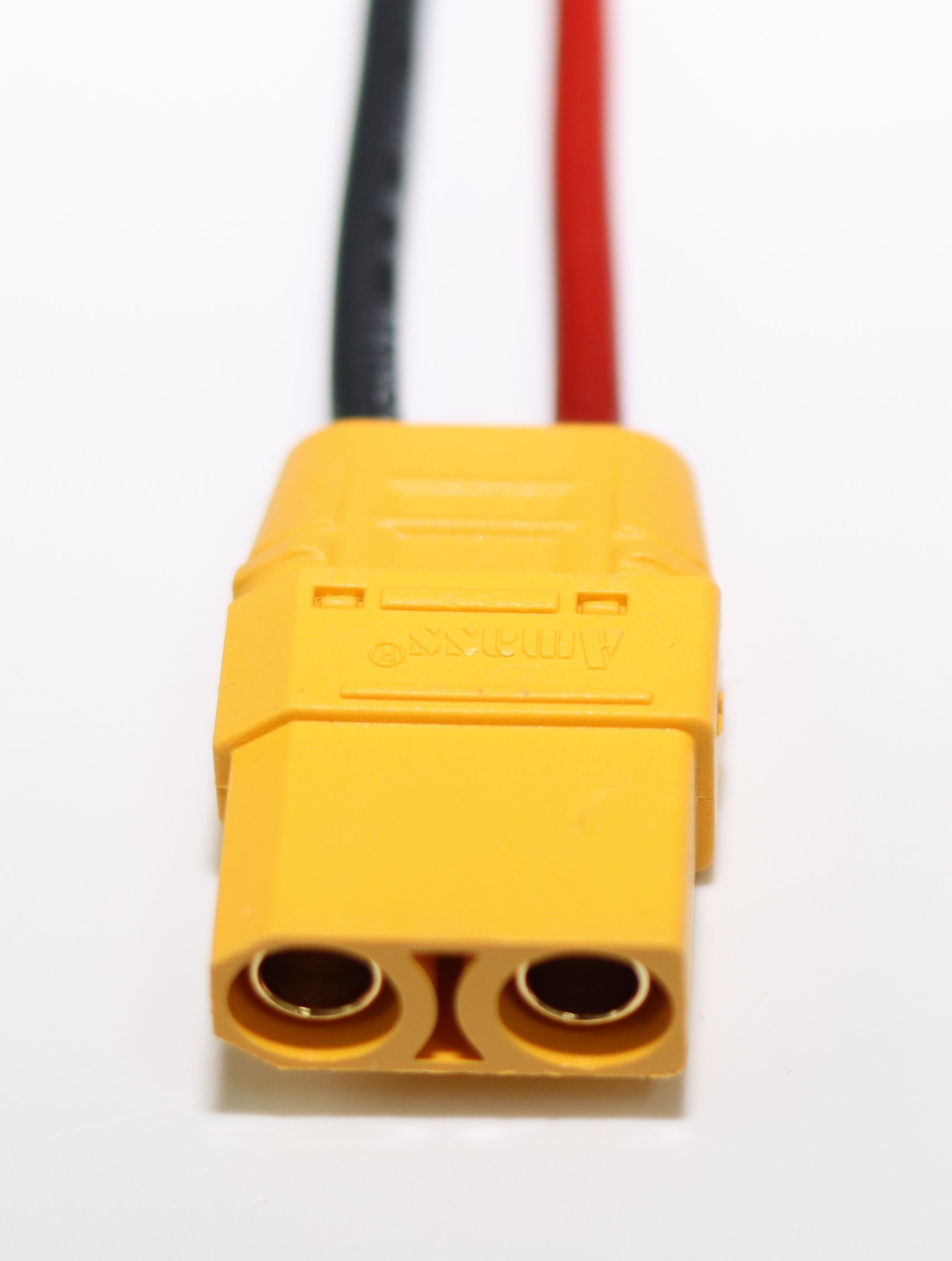 Ein gelber Stecker mit zwei Buchsen und roten und schwarzen Kabeln.