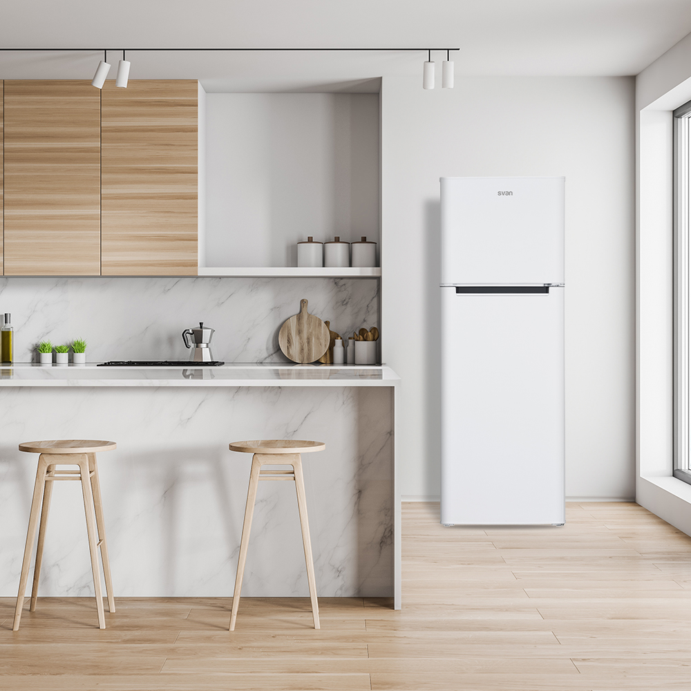 Nevera blanca junto a una encimera de cocina con mármol y armarios de madera.