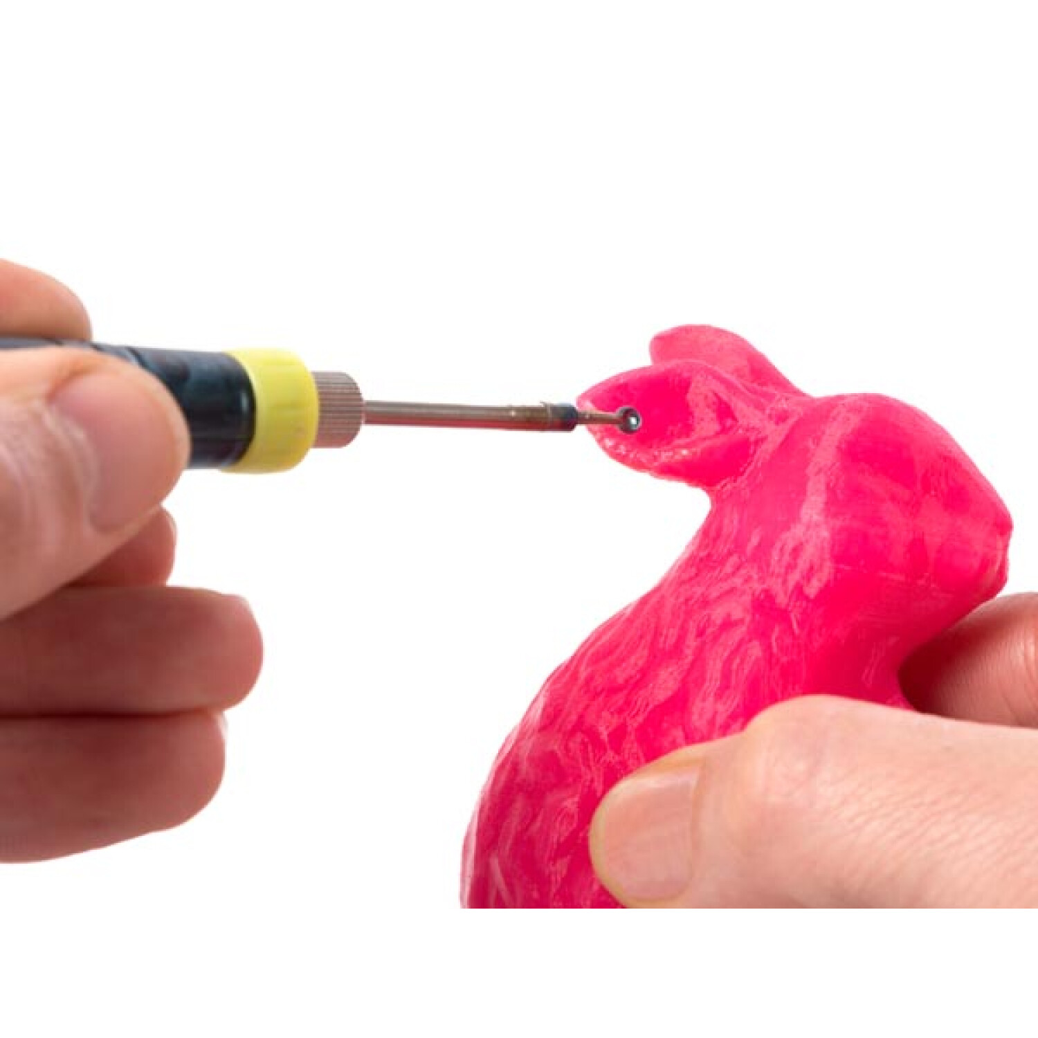 Mani che lavorano su una figura di coniglietto rosa con uno strumento.