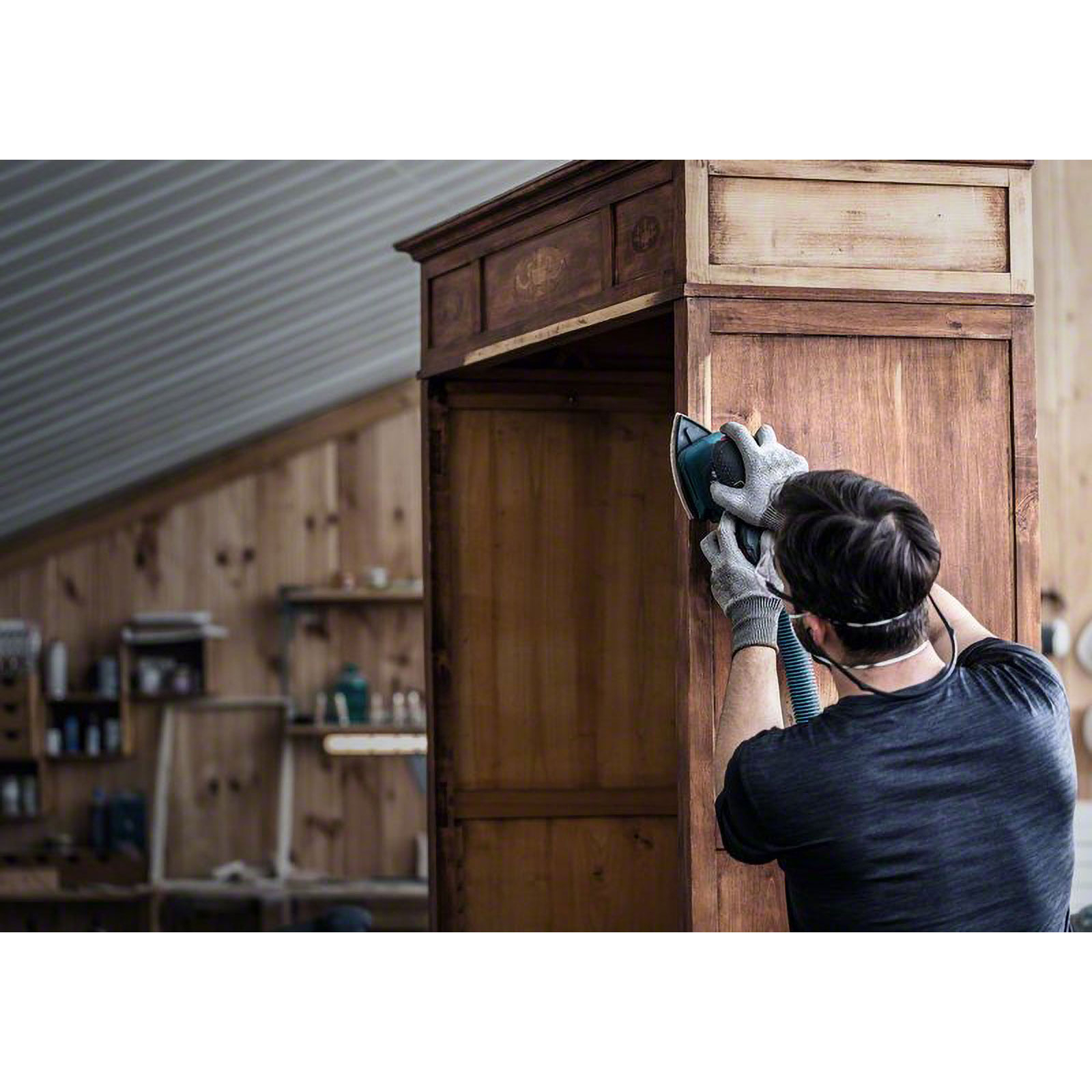 Mann schleift Holzschrank mit Exzenterschleifer in Werkstatt.