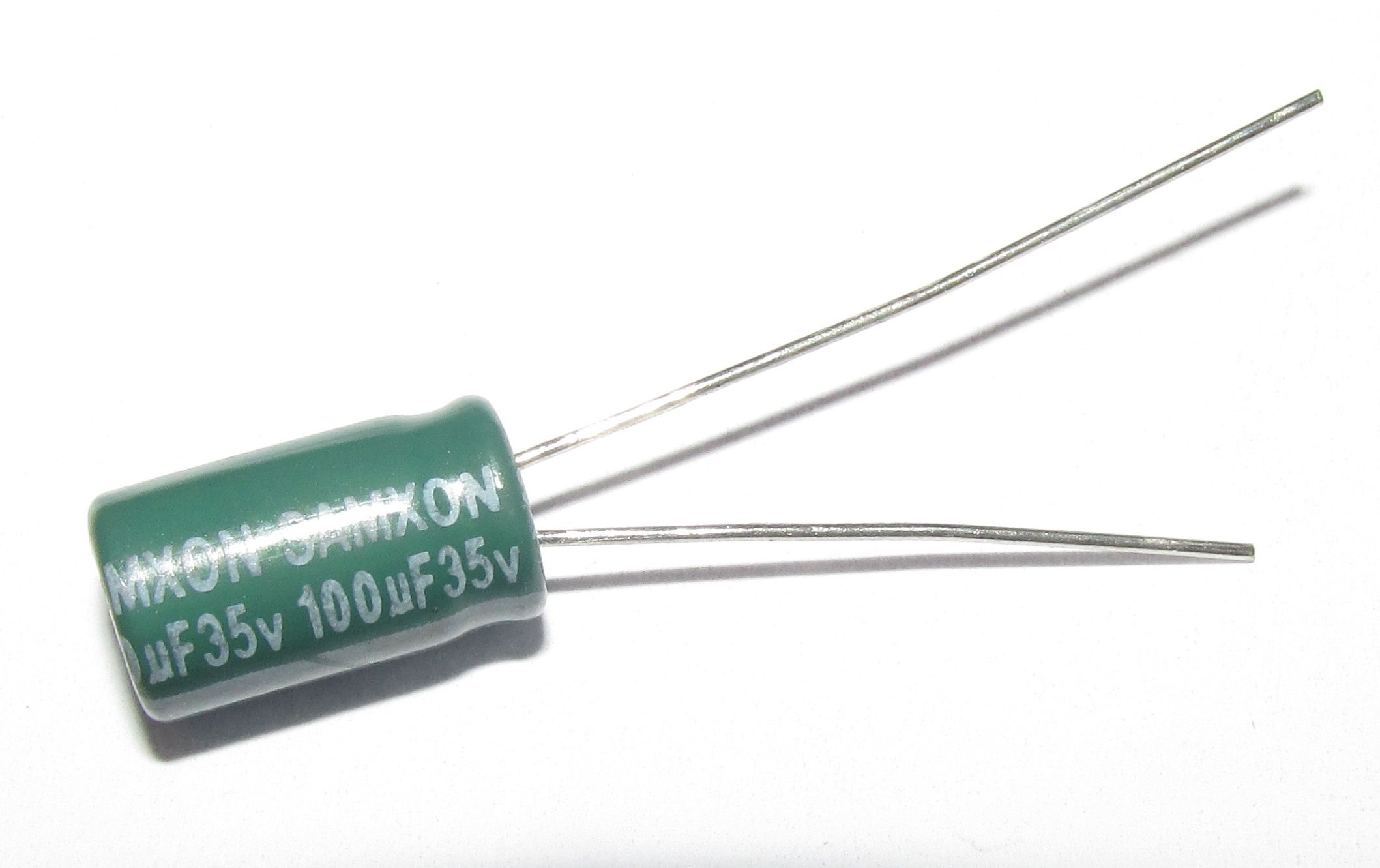 Grüner Kondensator mit 100µF 35V Beschriftung und zwei silbernen Drähten.