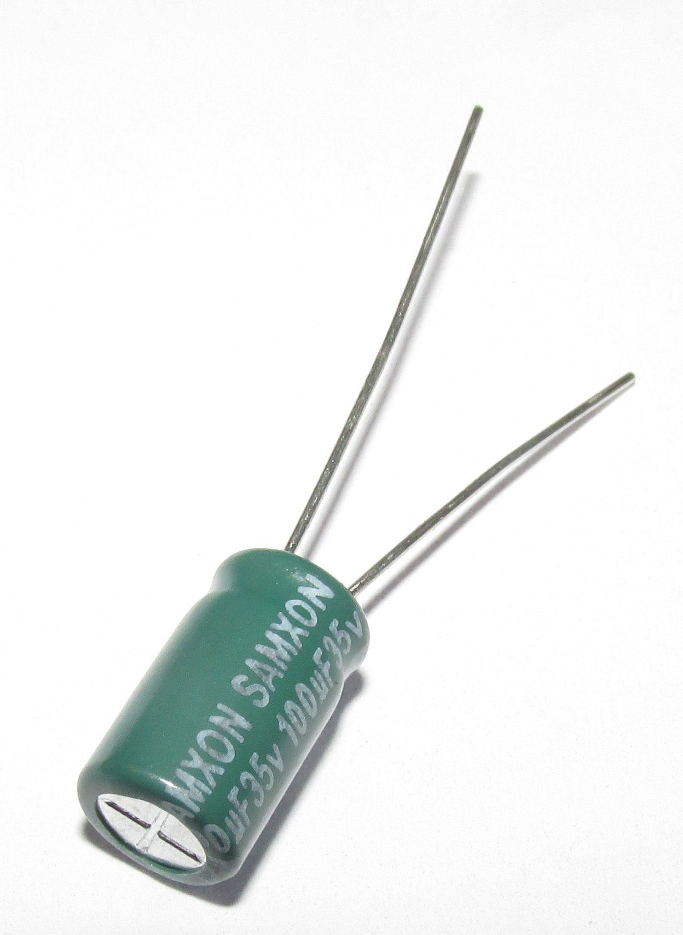 Grüner Samxon-Kondensator 100uF 35V mit zwei silbernen Drähten auf weißem Hintergrund.