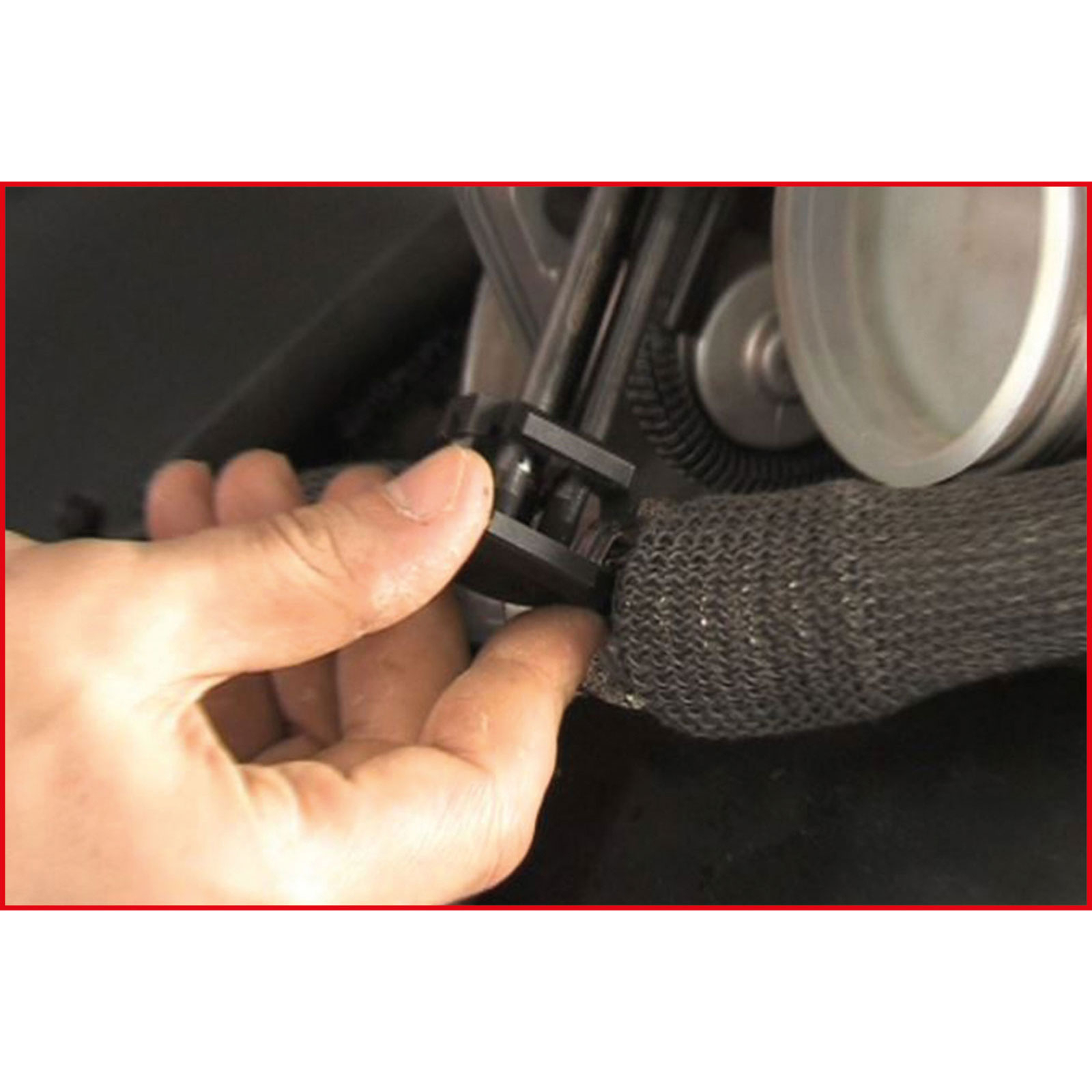 Hand befestigt schwarzen Clip an grauem Stoffrohr mit Zahnrad im Hintergrund.