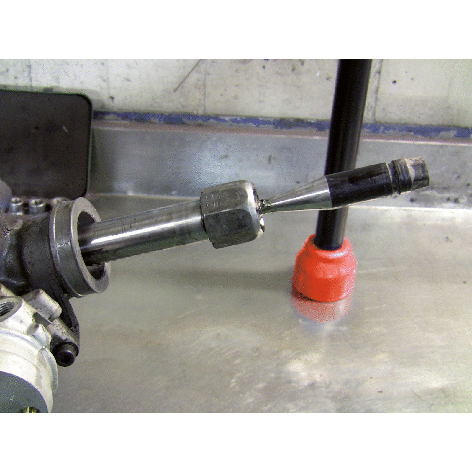 Aste metalliche con dado e base arancione su tavolo.