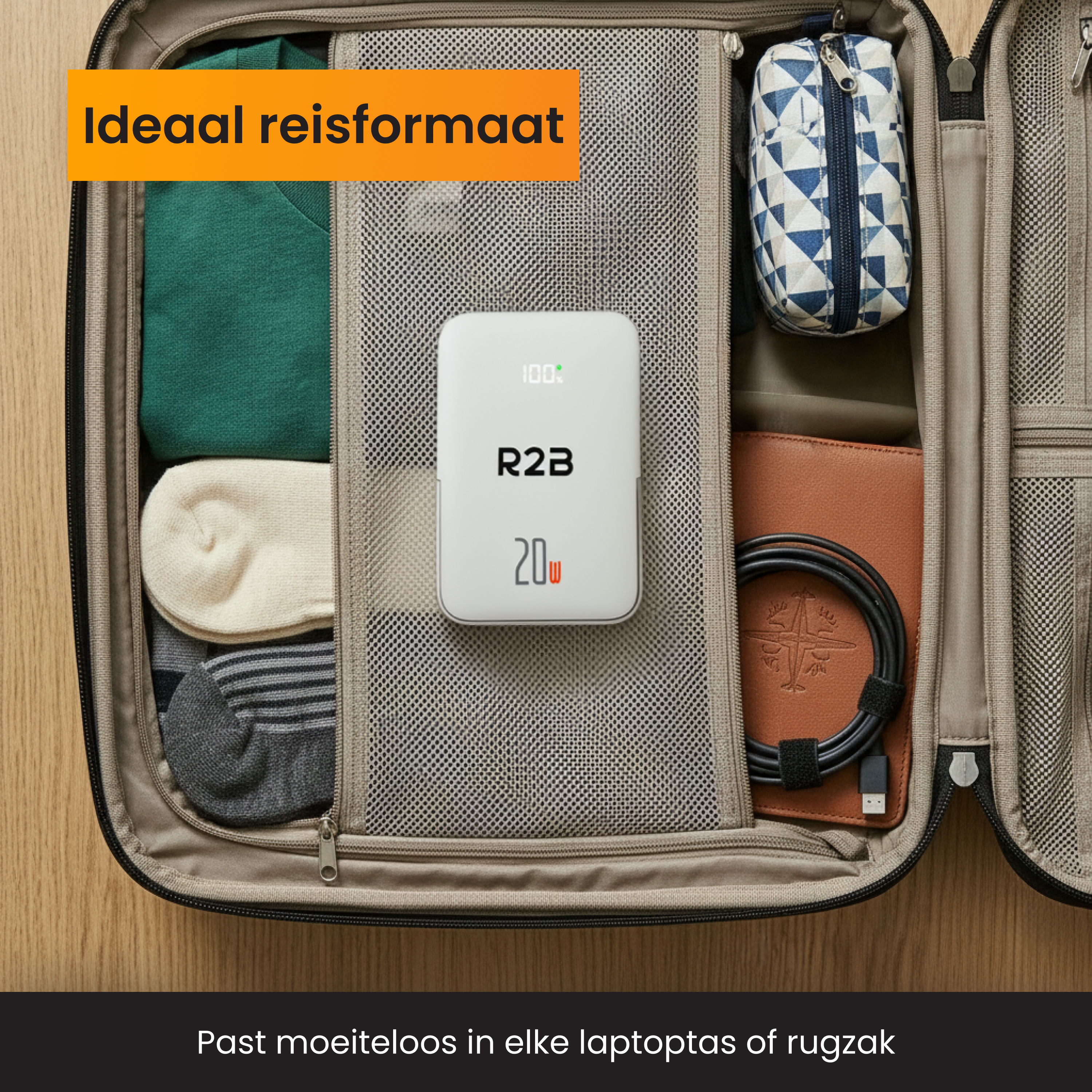 An open suitcase packed with clothes, socks, a charger, and a cable.
