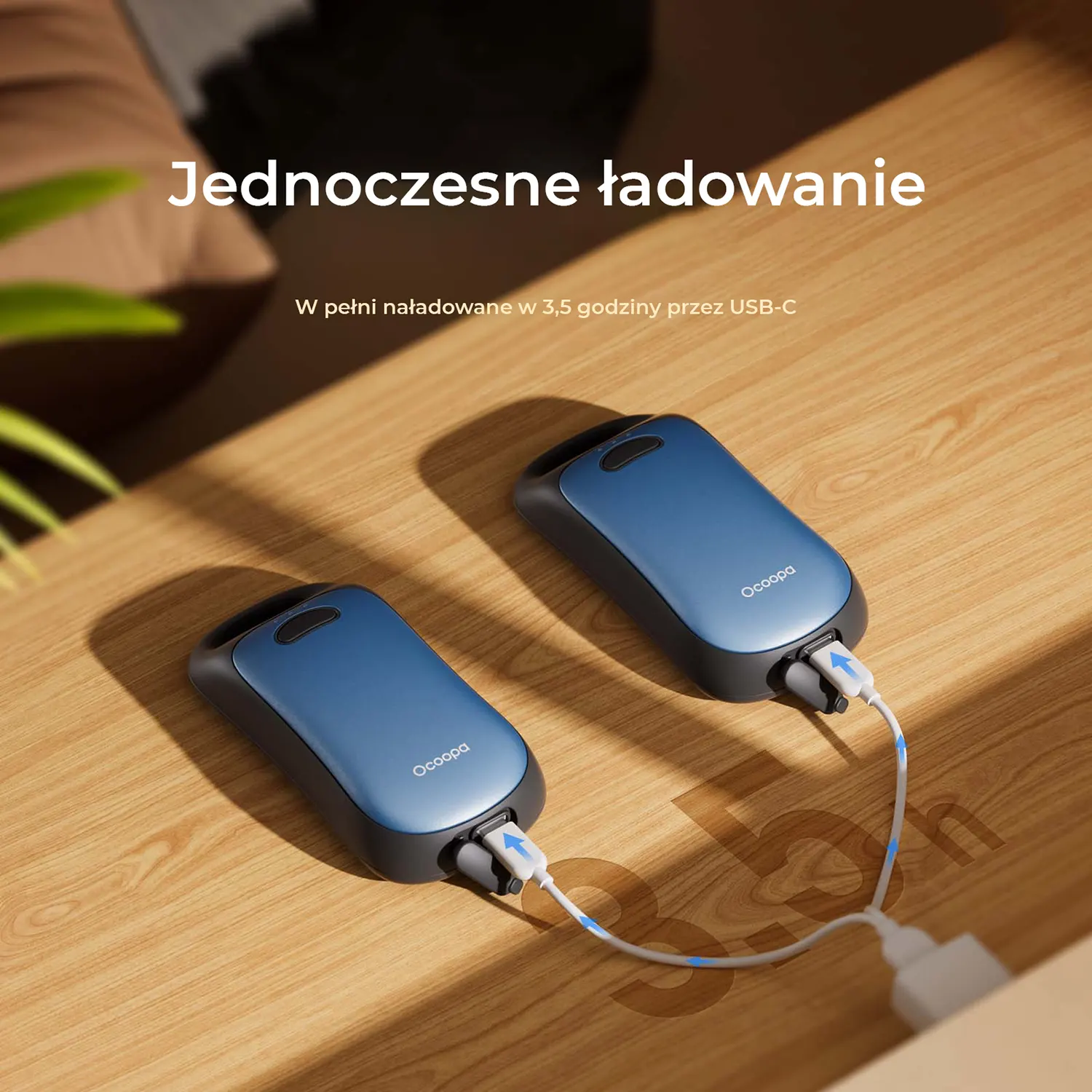 Dwa niebieskie ładowarki podłączone kablami USB. Leżą na drewnianym stole.
