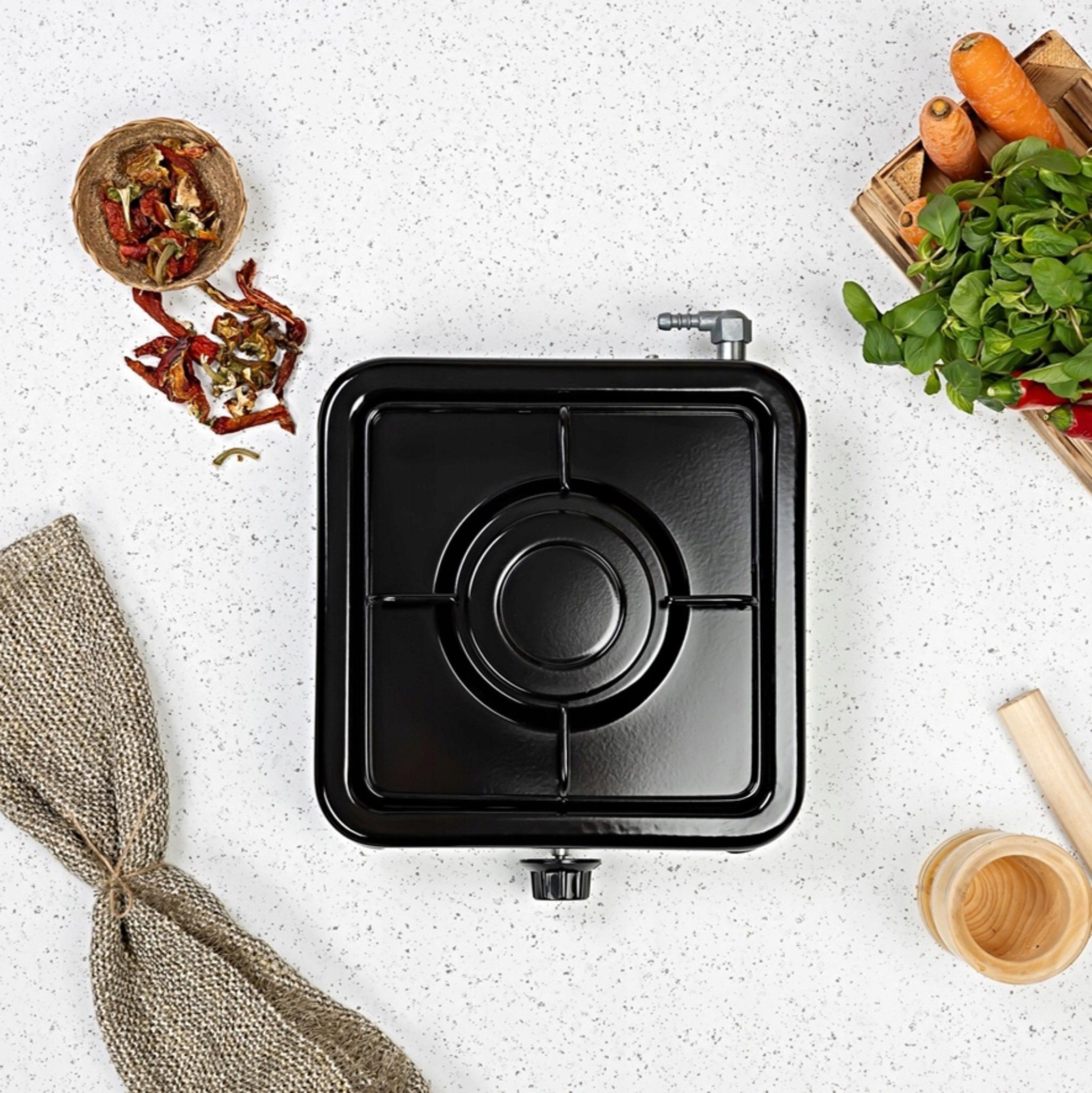 Czarna kuchenka gazowa z suszoną papryką, marchewką i zieleniną.