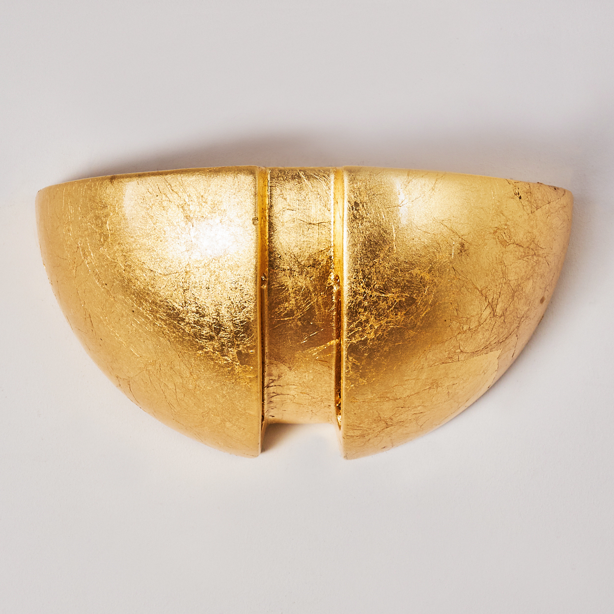 Goldene, halbmondförmige Wandleuchte mit vertikalen Rillen und strukturierter Oberfläche.